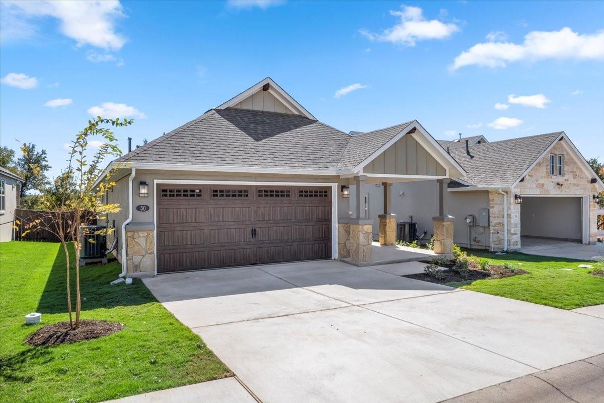 Gray single-story home with a wide double garage, stone accents, and a concrete driveway.
