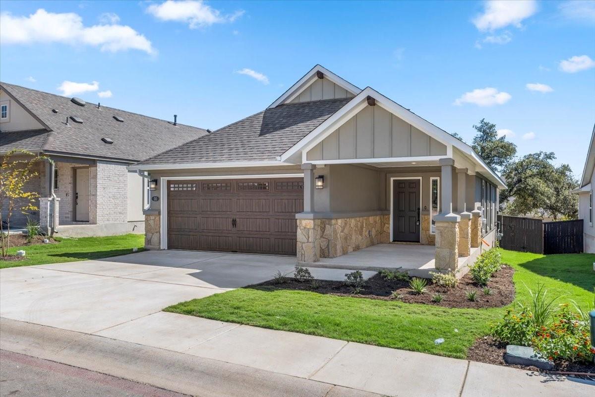 Single-story home with a wide two-car garage, covered entry, and stone accents.