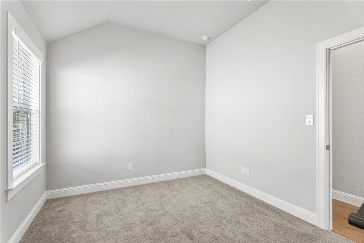 Empty carpeted room with a window and white blinds.