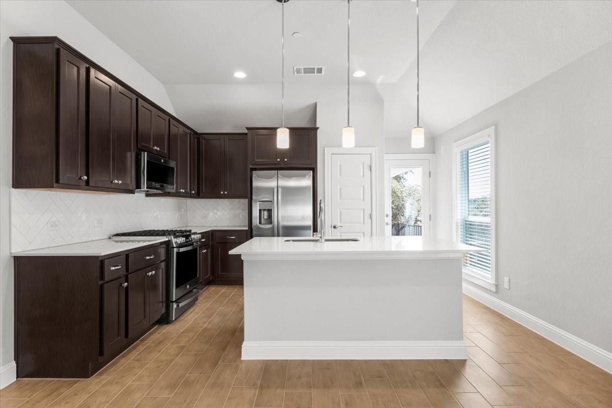Kitchen with dark cabinets, stainless steel appliances, and a large white island.