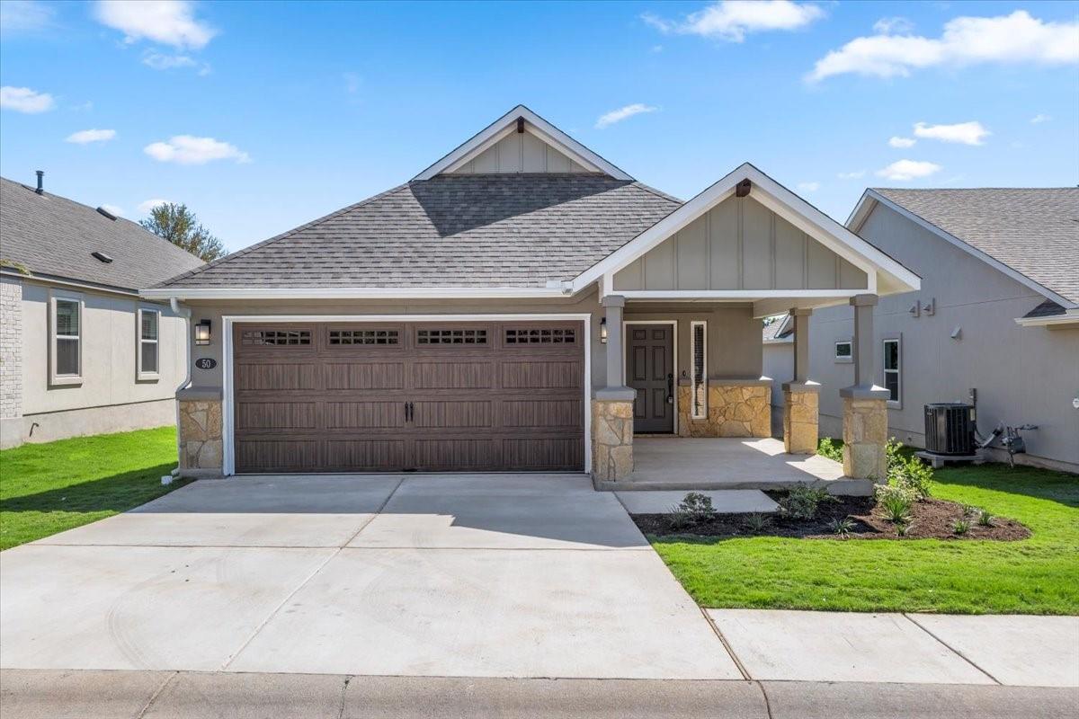Single-story home with a wide double garage, covered entry, and stone accents.