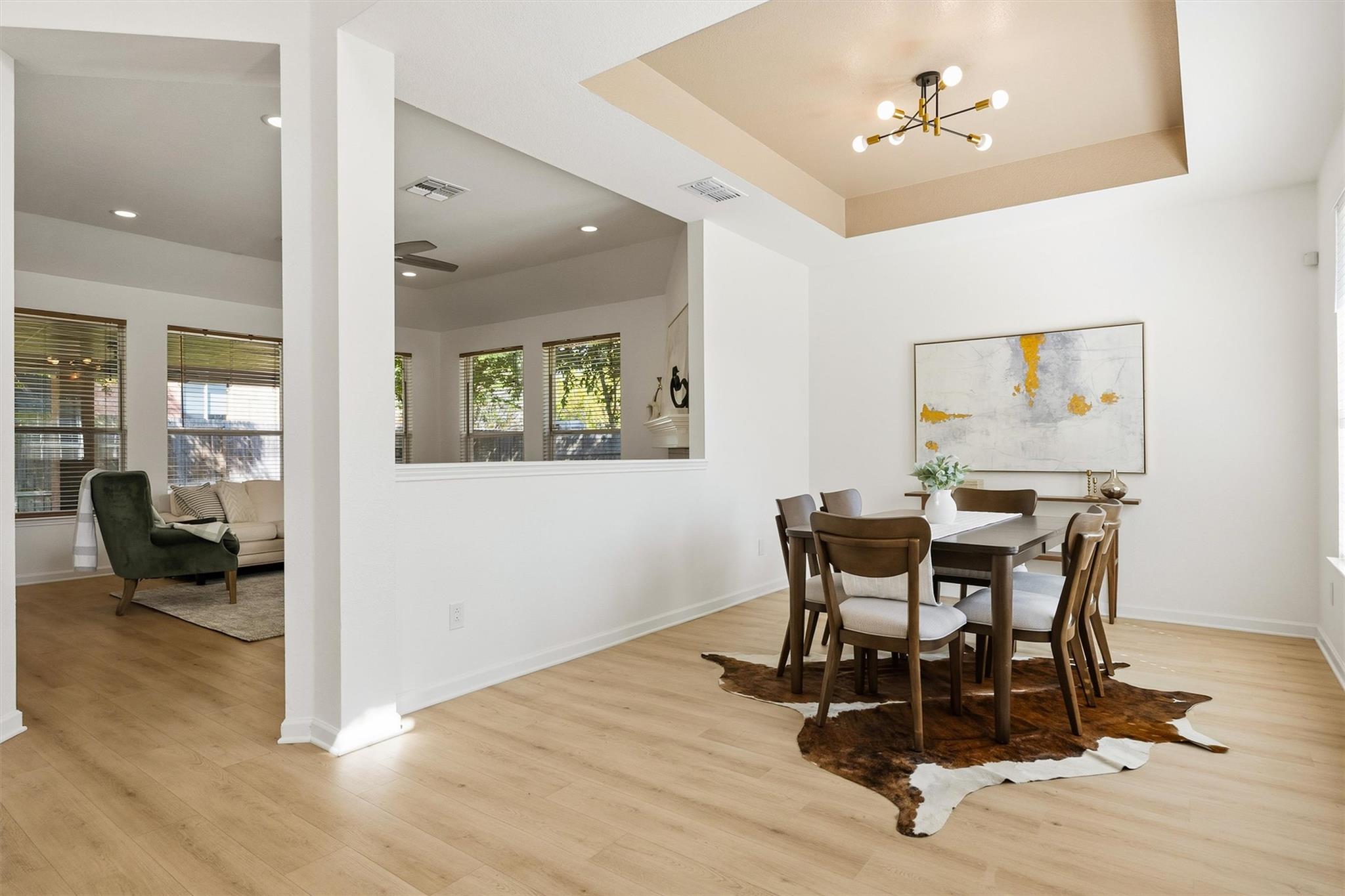 Dining room with a dark wood table beneath a brass chandelier, opening onto a living area.