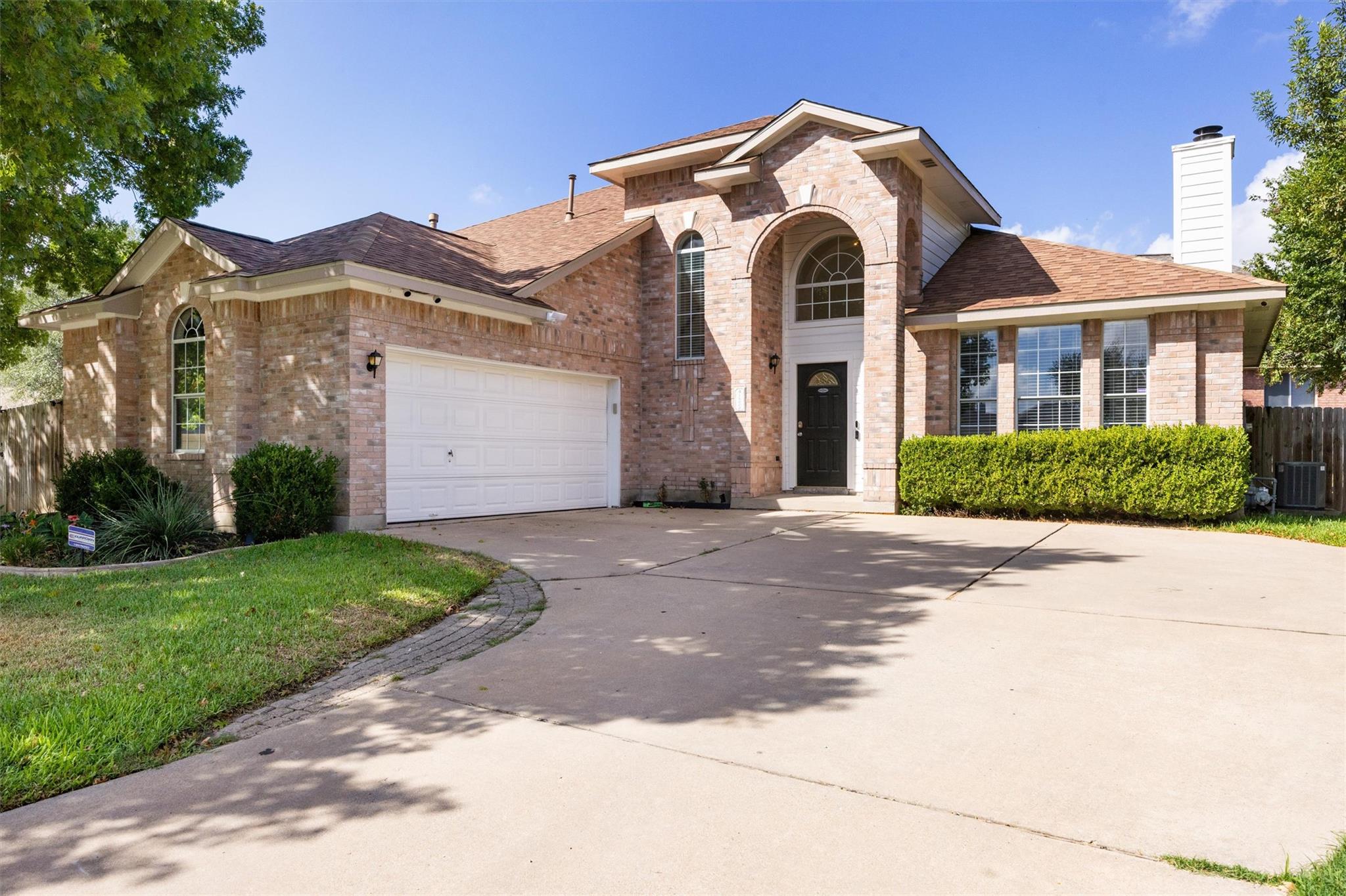 Brick house with an arched entry, double garage, and broad concrete driveway.