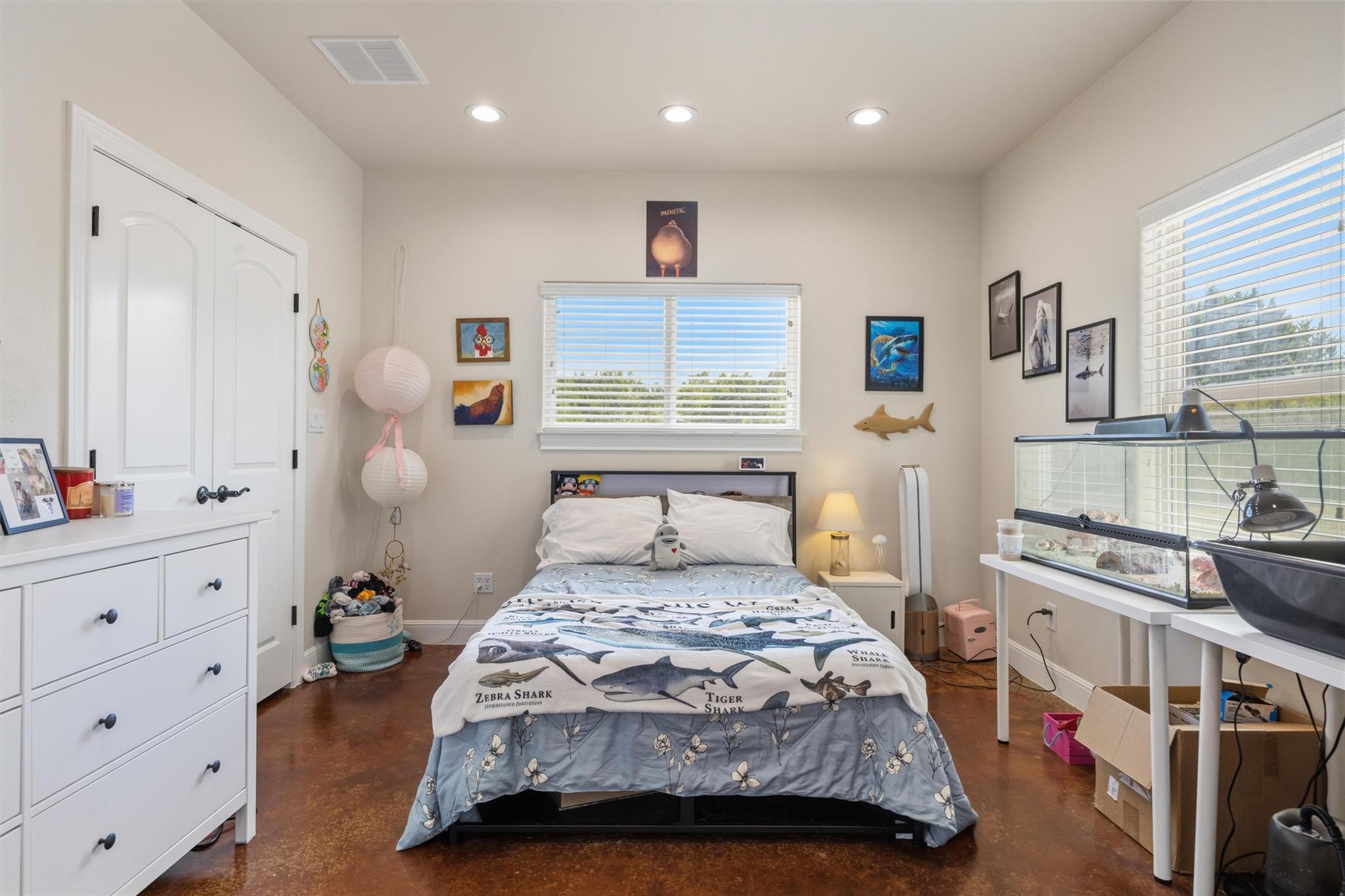 Bedroom with shark-themed bedding, sea-life artwork, and a large aquarium beside the bed.