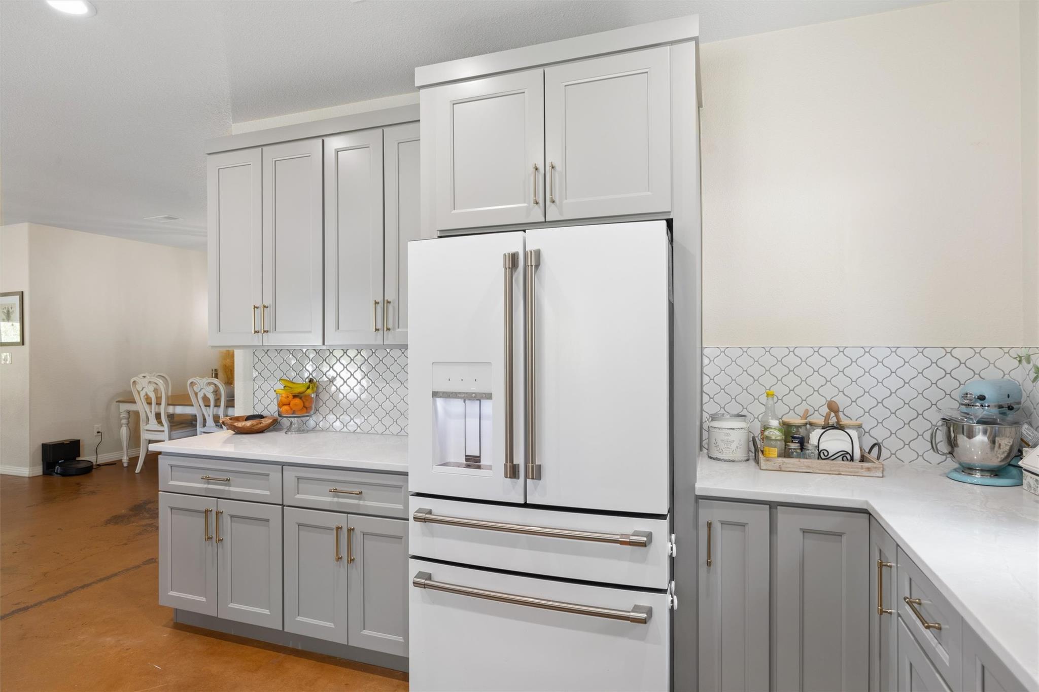 Kitchen with gray cabinets, patterned tile backsplash, and a large white French-door refrigerator.