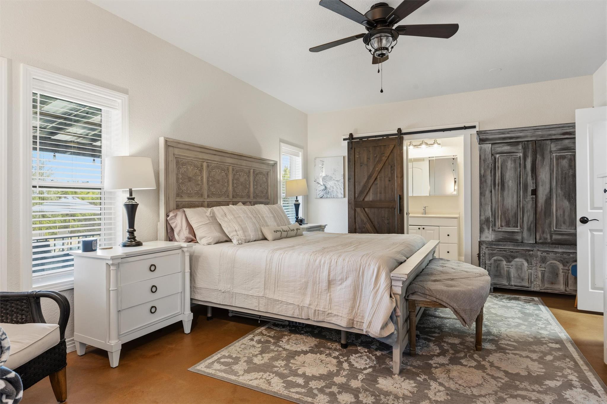 Furnished bedroom with a carved wood headboard, sliding barn door, and dark armoire.