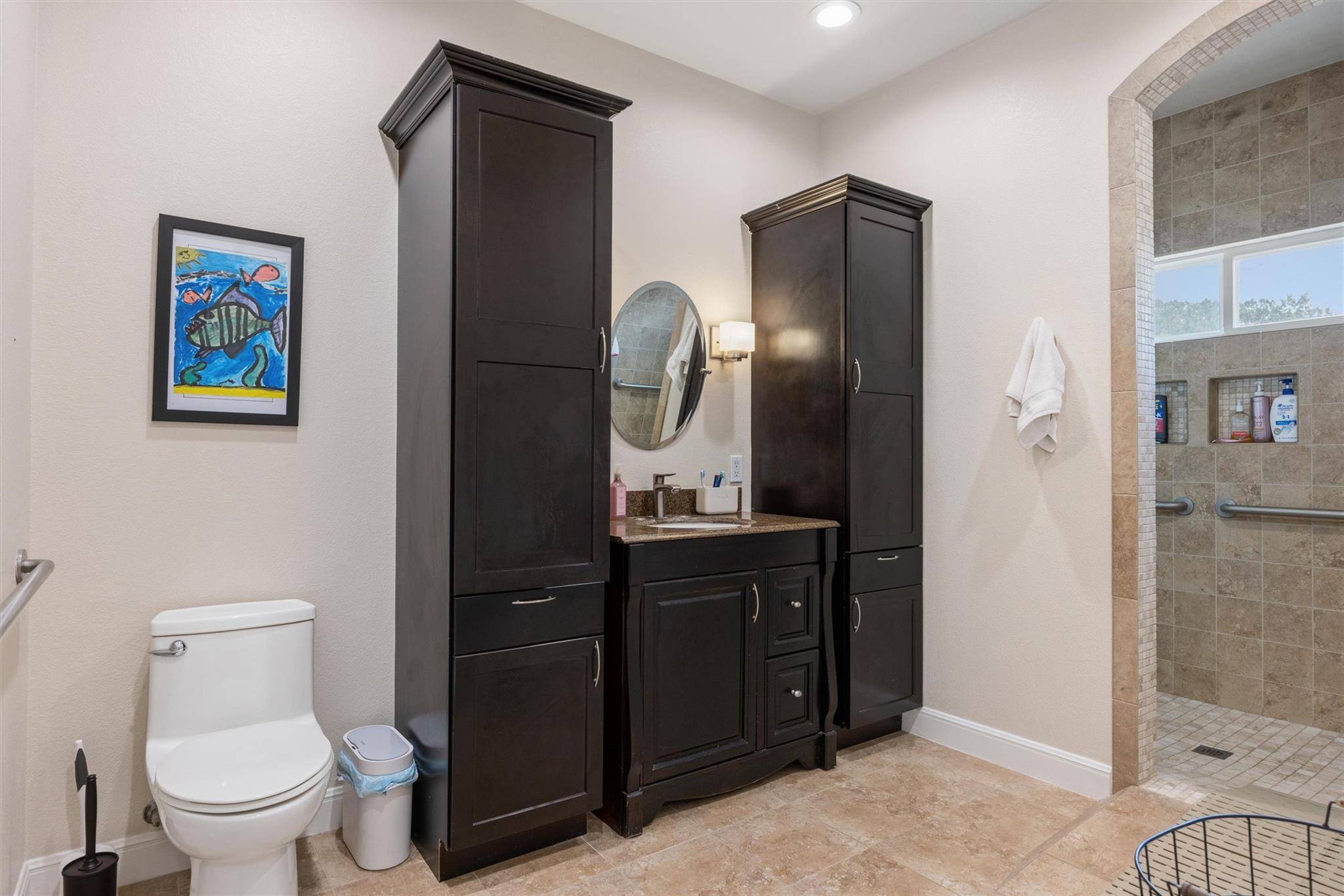 Bathroom with dark built-in vanity cabinets and a tiled walk-in shower.