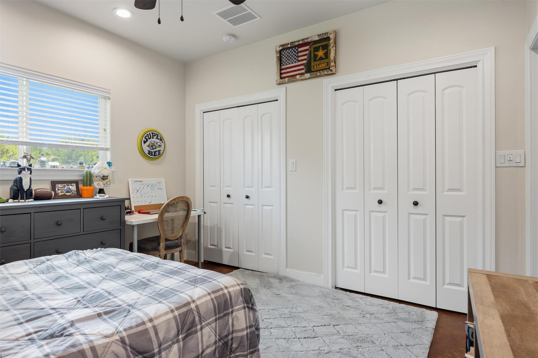 Bedroom with plaid bedding, white closets, a window, and a small desk.
