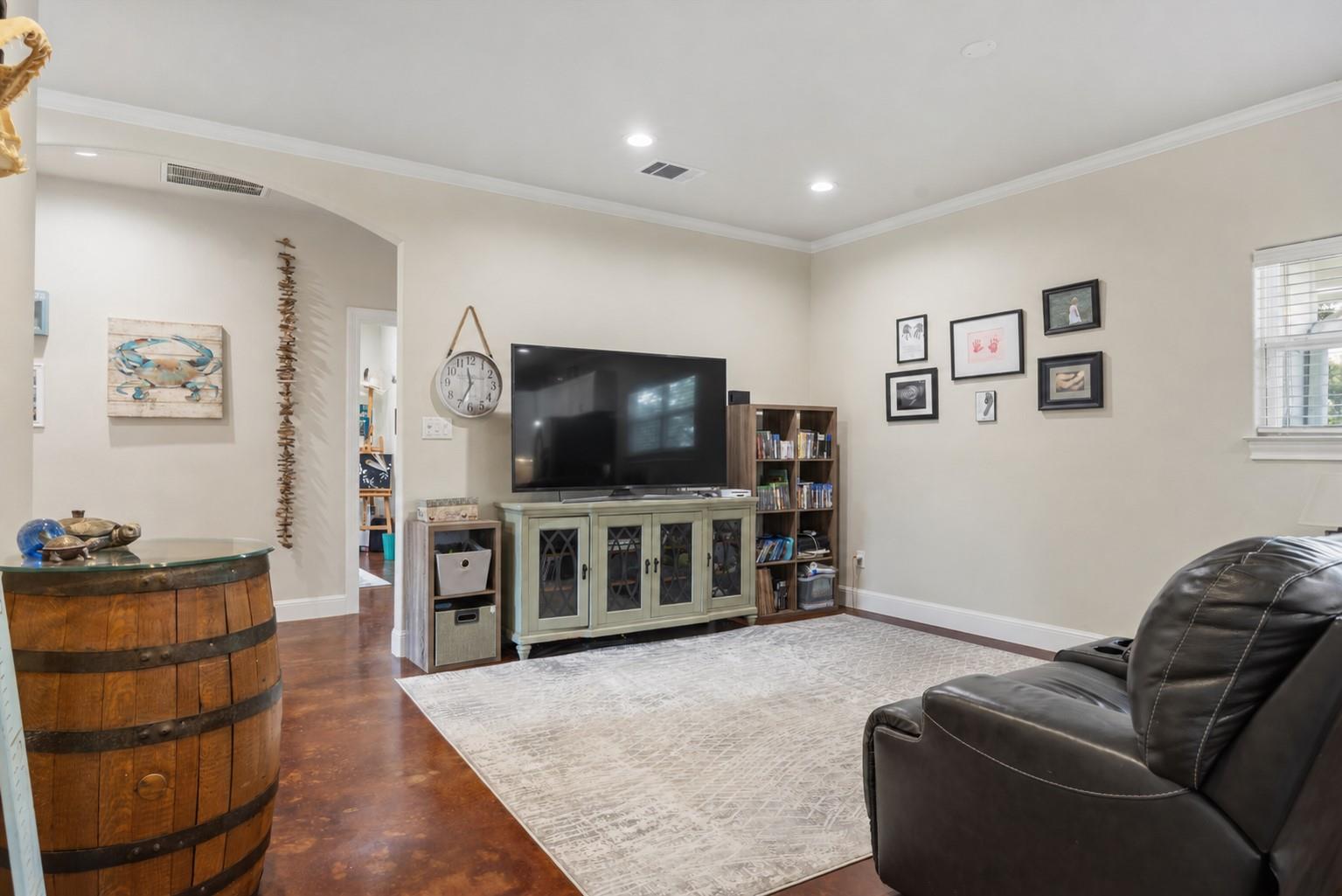 Living room with a large television, pale green media cabinet, leather recliner, and patterned area rug.