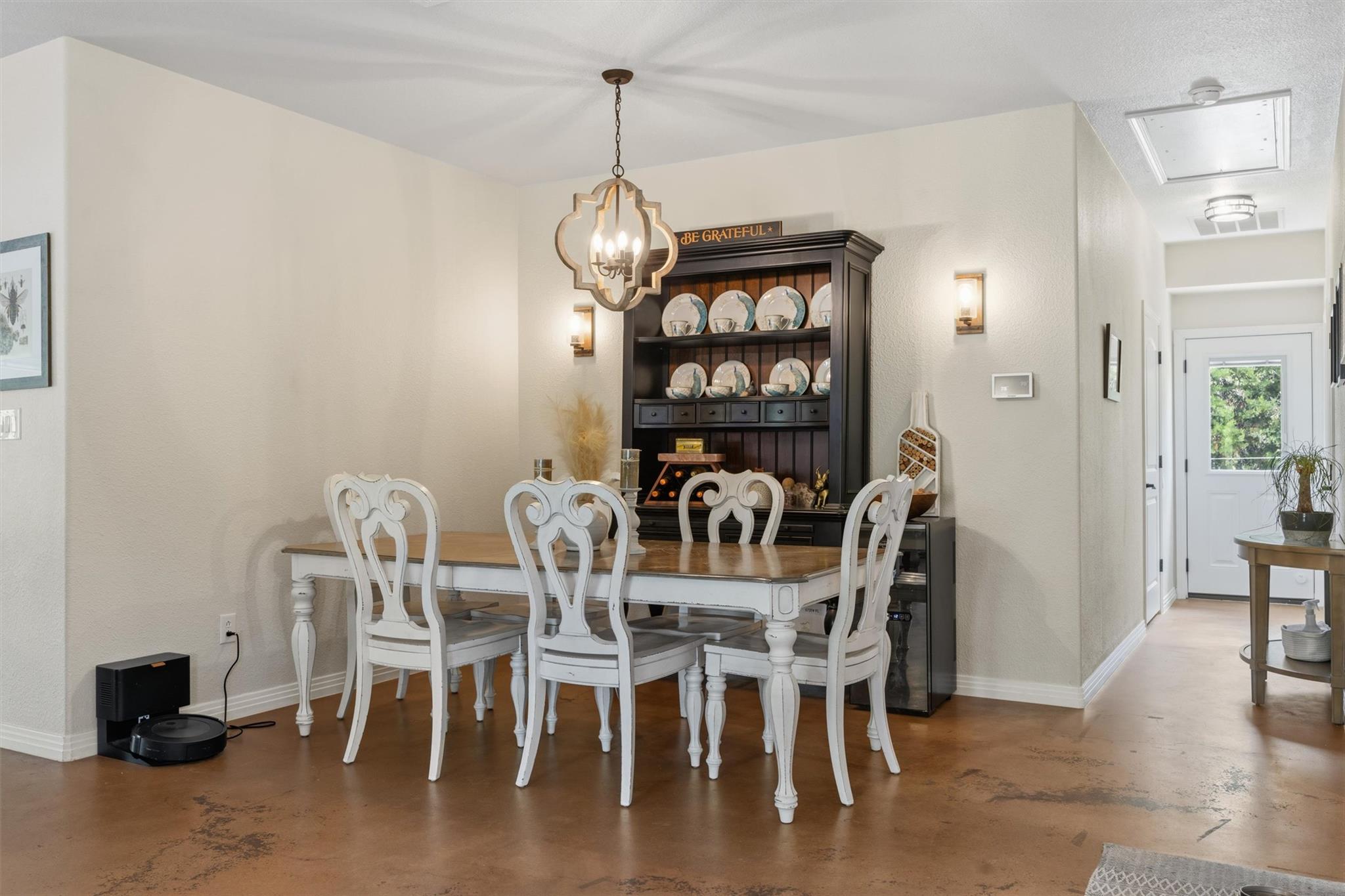 Dining room with ornate white chairs, a dark china hutch, and polished concrete floors.