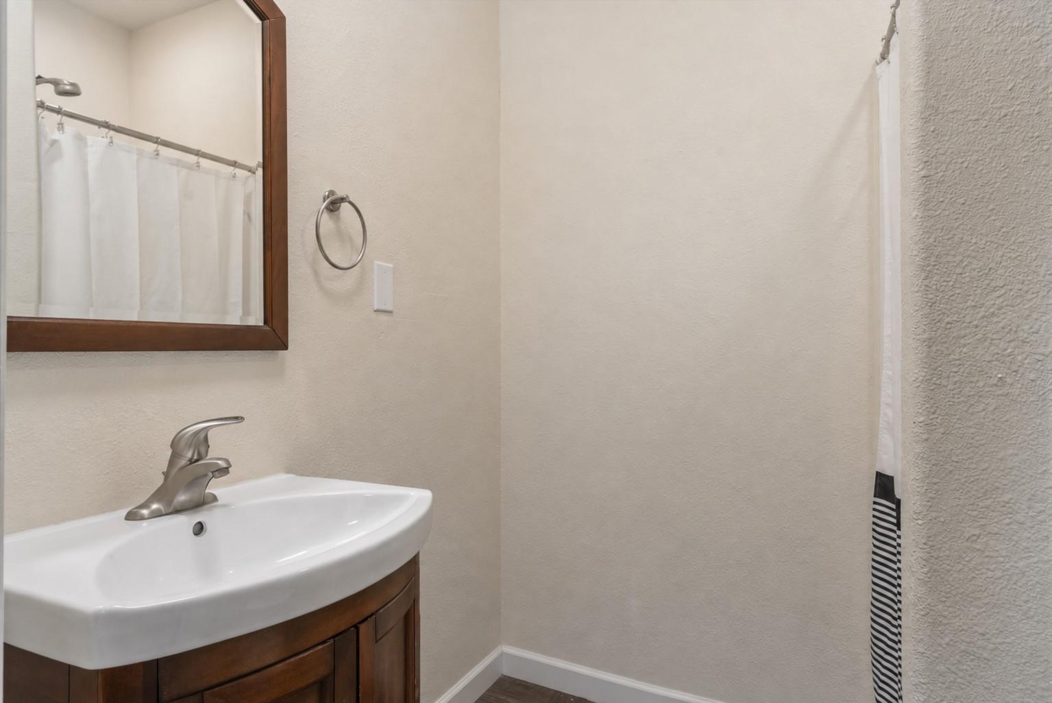 Bathroom with a white sink, dark wood vanity, framed mirror, and striped shower curtain.