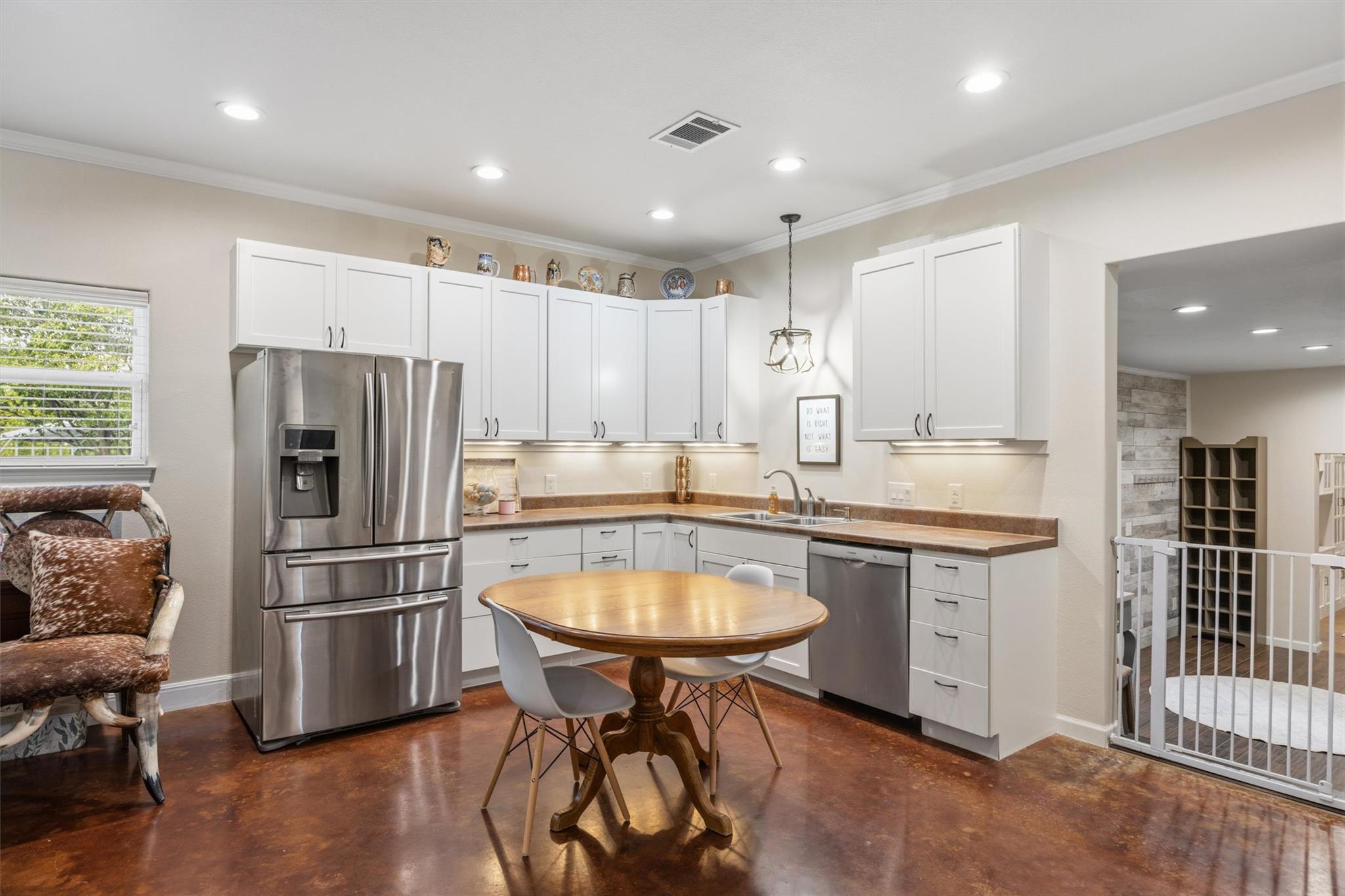 Kitchen with white cabinets, stainless steel appliances, and a round wooden table.