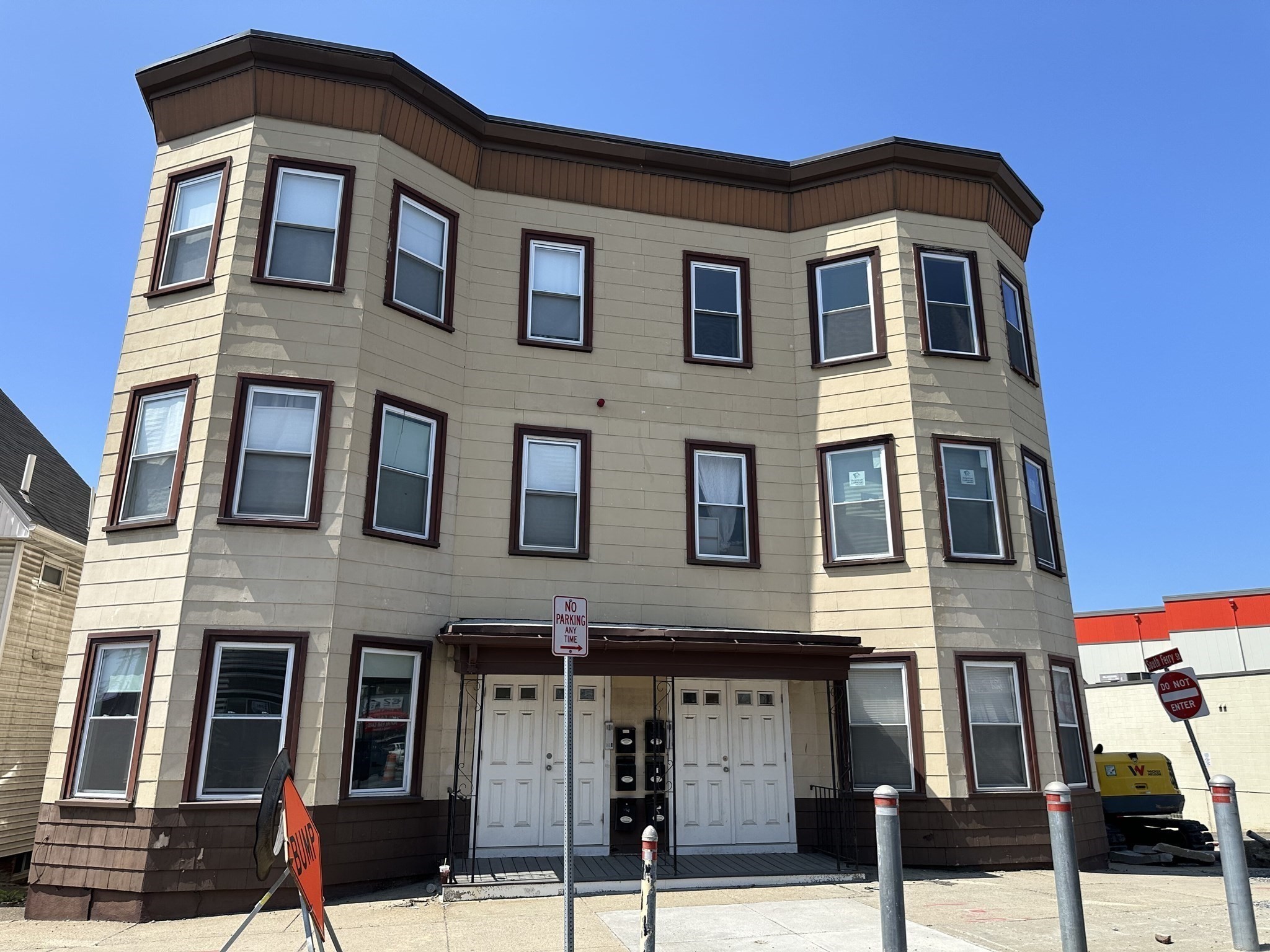 Three-story beige apartment building with bay windows and two white entry doors.