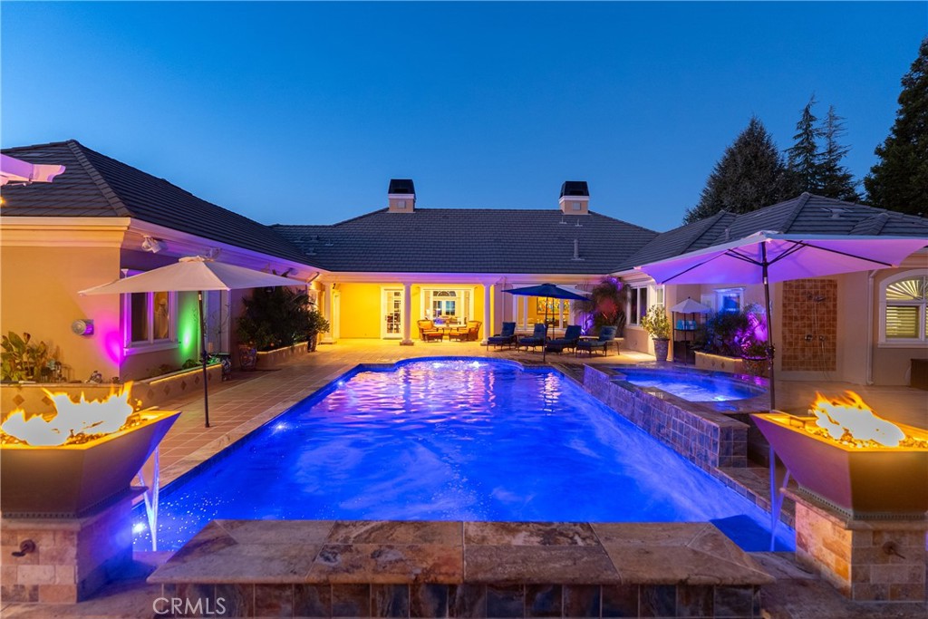 Courtyard pool and raised spa at night, with colorful lighting and fire bowls.