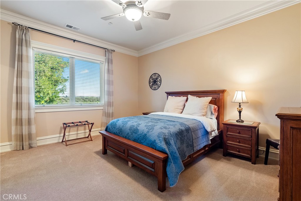 Bedroom with a blue quilted bed, dark wood furniture, and a large window overlooking greenery.