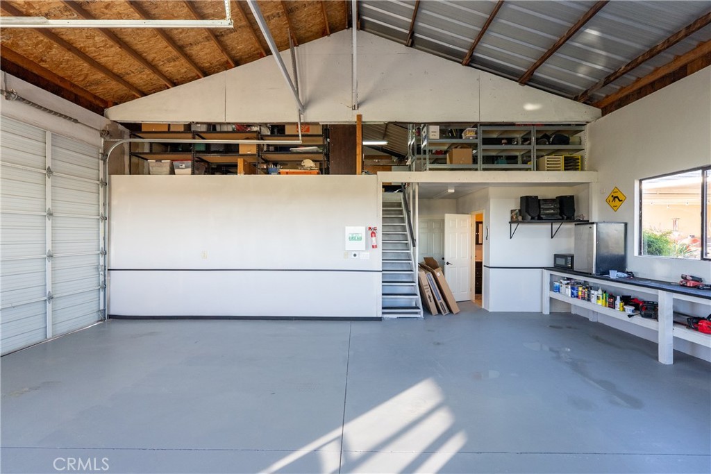 Spacious garage workshop with an overhead storage loft, staircase, and built-in workbench.