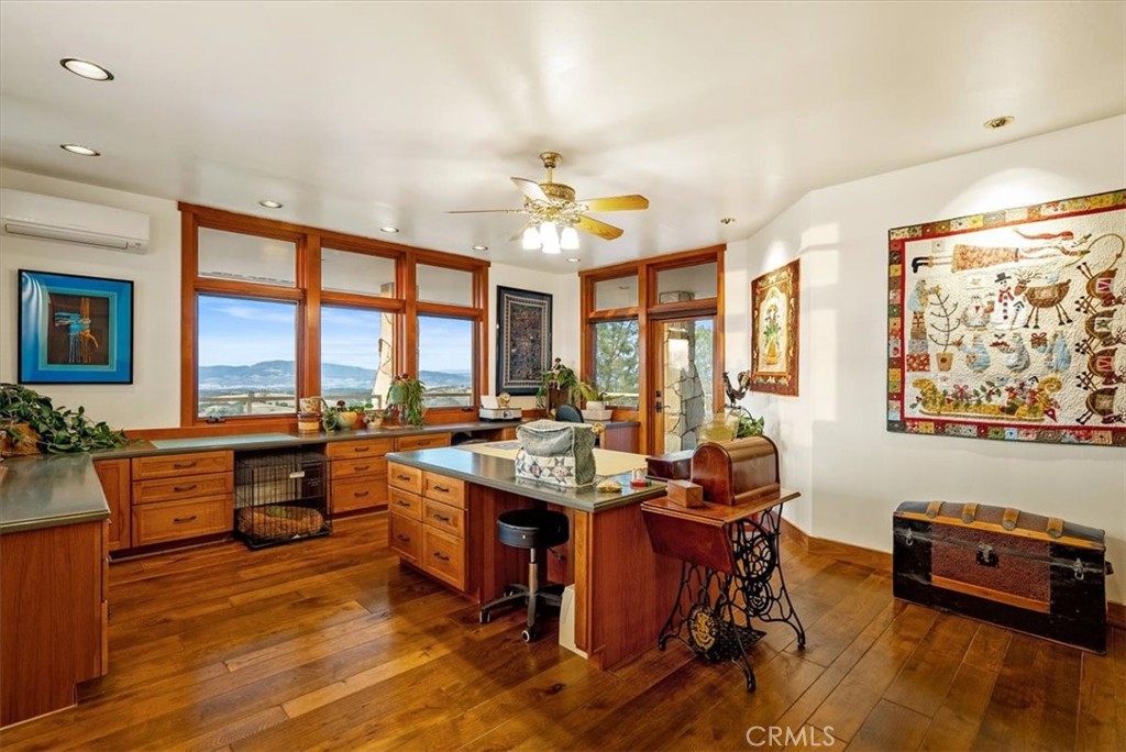 Kitchen with warm wood cabinetry, a central island, and broad windows overlooking distant hills.