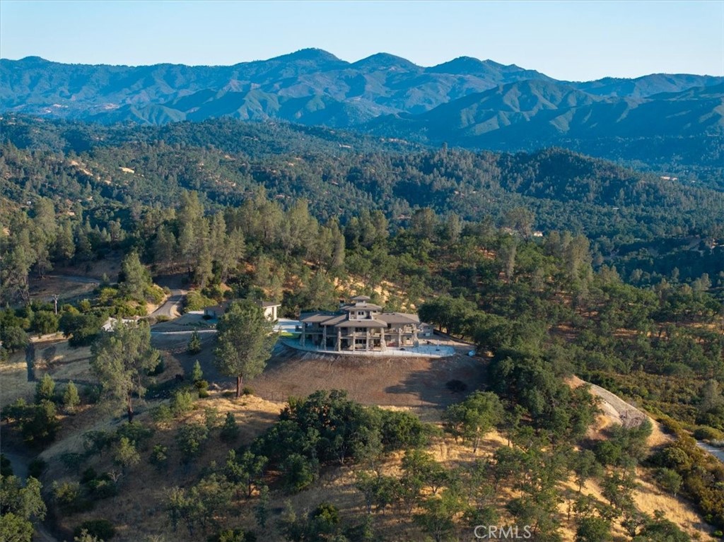 Rural home amid wooded hills, with a mountain range in the background.
