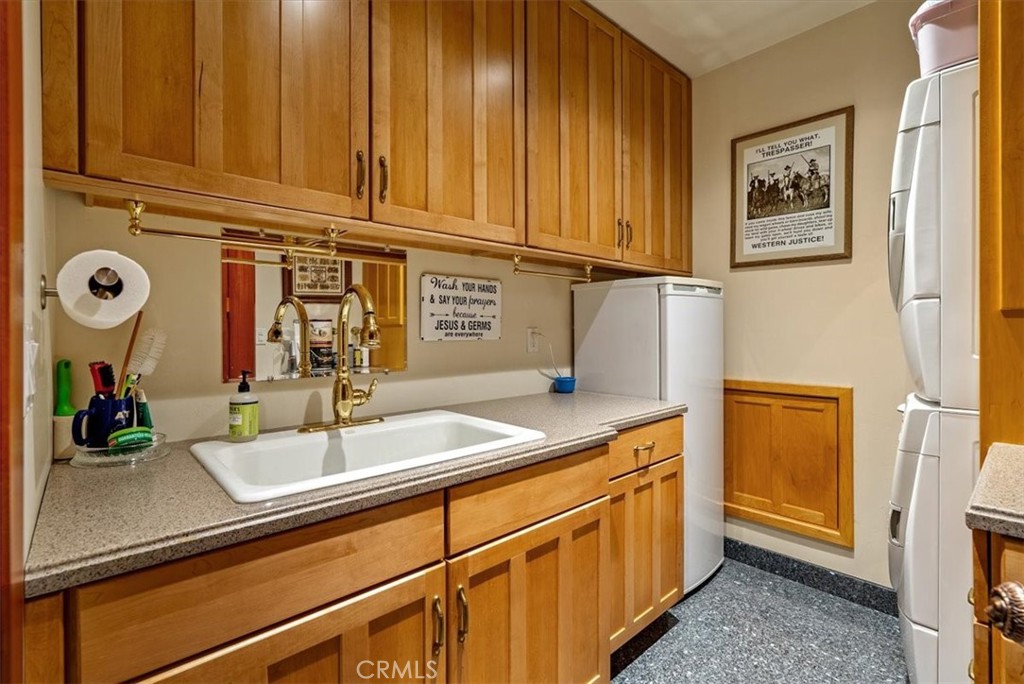 Laundry room with extensive wood cabinetry, a utility sink, and white washer and dryer.