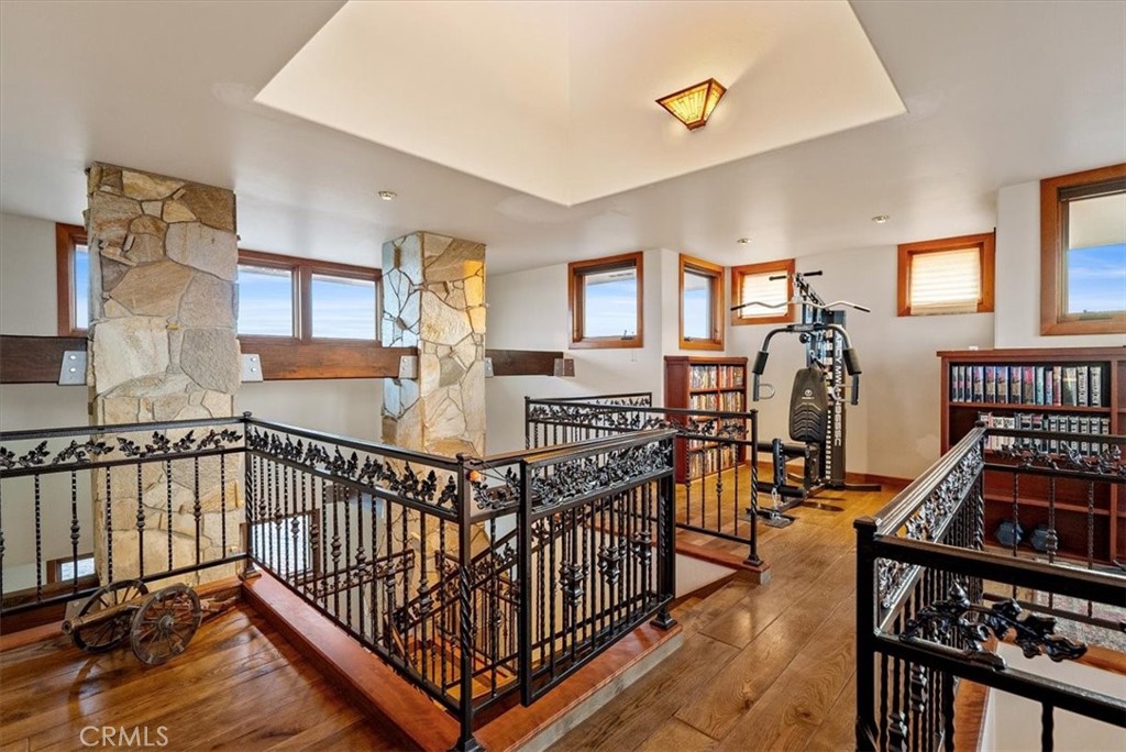 Exercise room with ornate railings, stone columns, exercise equipment, and built-in bookshelves.
