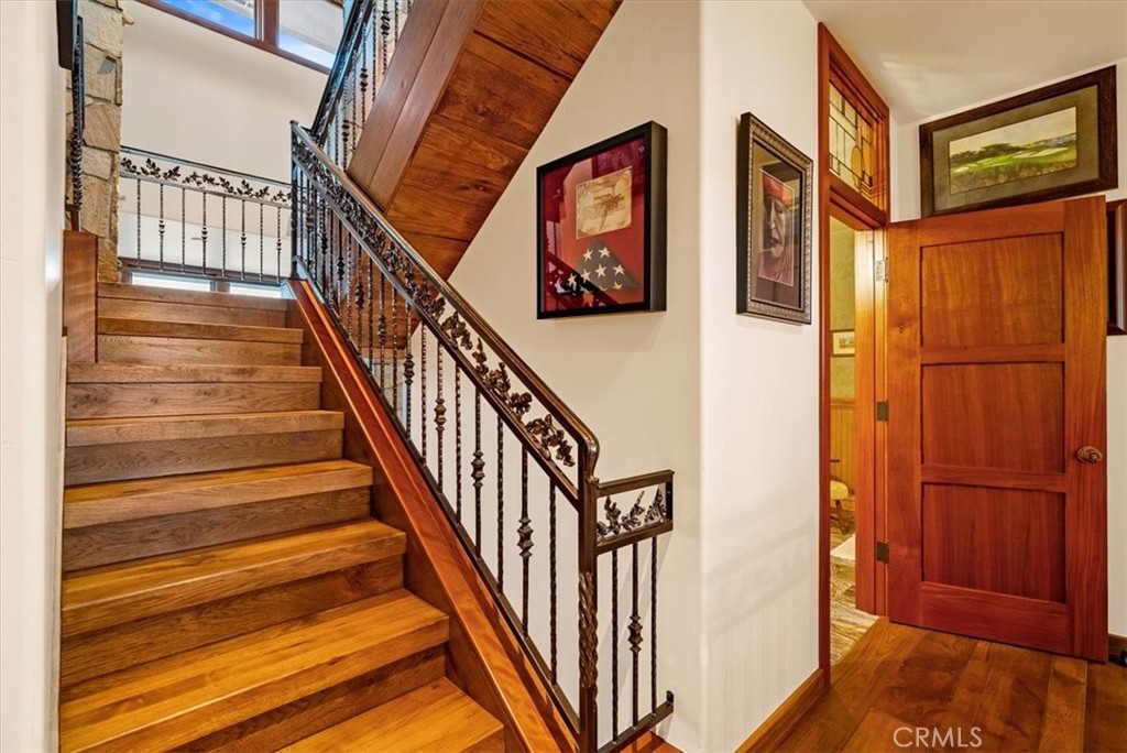 Wooden staircase with ornate iron railing and an open wood door.
