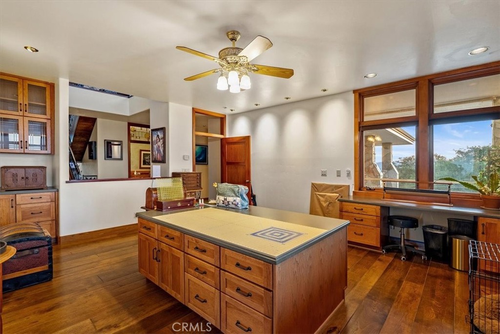 Kitchen with a large wood island, extensive cabinetry, hardwood floors, and broad windows overlooking trees.