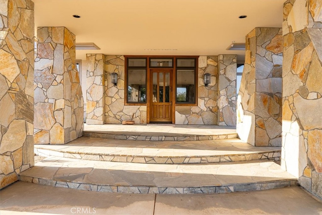 Stone-clad front entrance with broad curved steps and a wooden door.