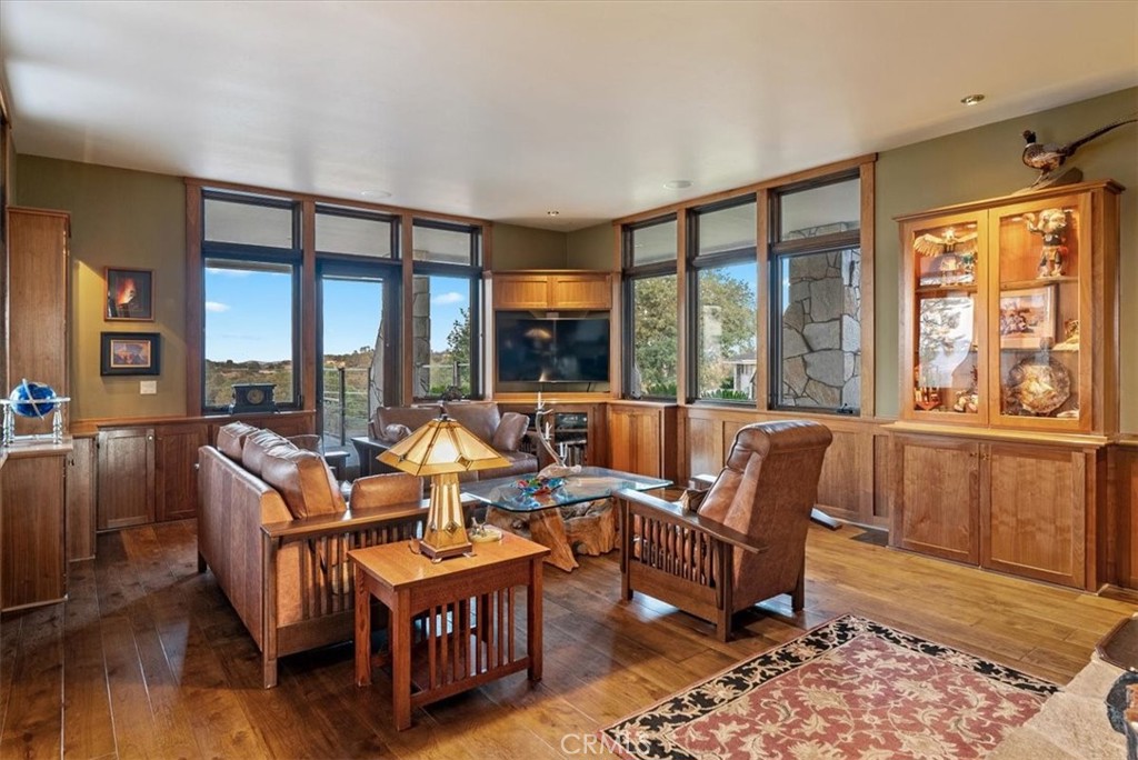 Living room with leather seating, wood paneling, and large windows.