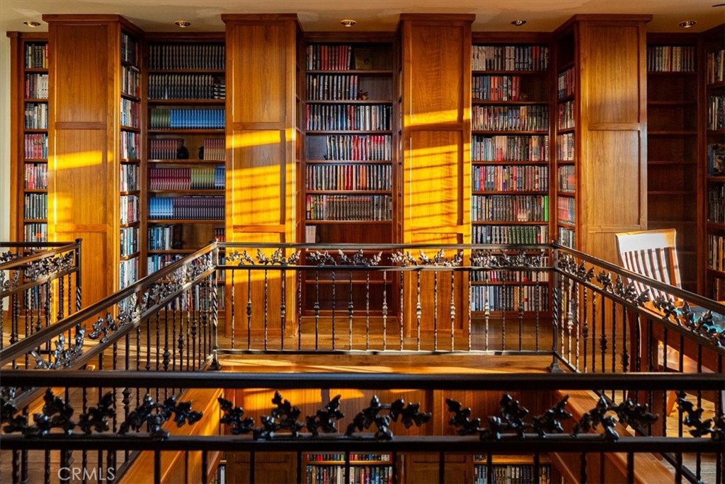 Two-story library with packed wooden bookshelves, a mezzanine, and ornate metal railings.