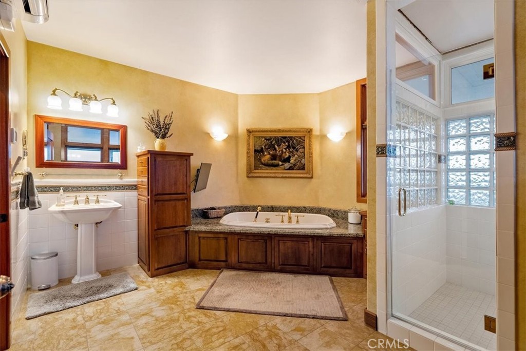 Bathroom with a built-in soaking tub, wood vanity, and separate glass-block shower.