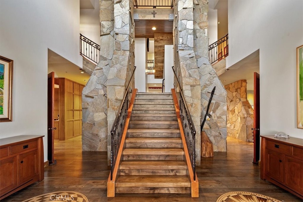 Two-story foyer with a broad stone staircase, wrought-iron railings, and stone pillars.