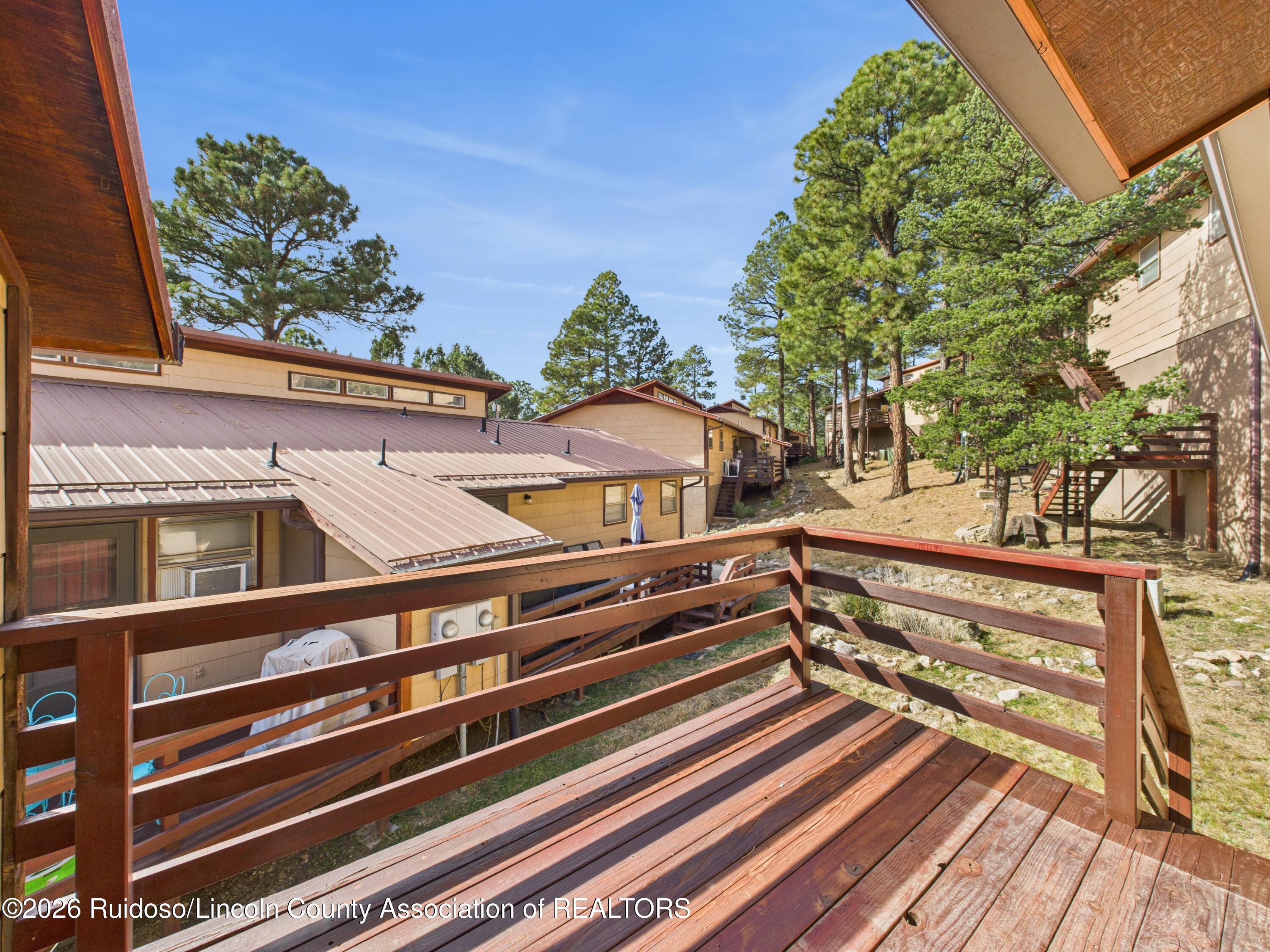 Wooden deck overlooks neighboring condos and pine trees in Ruidoso.