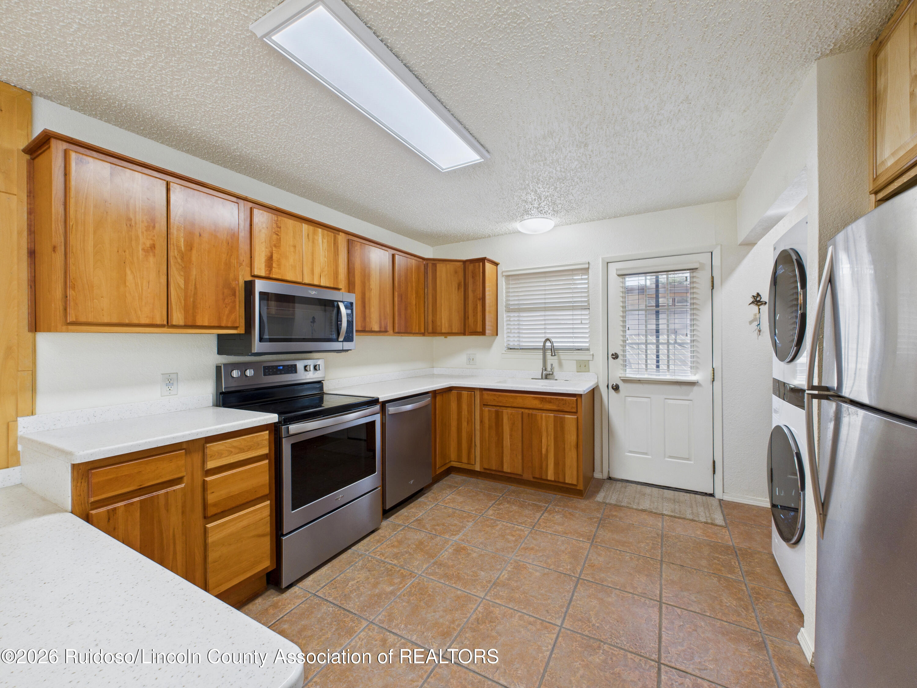 Kitchen with wood cabinets, white countertops, stainless steel appliances, and a glass-panel exterior door.