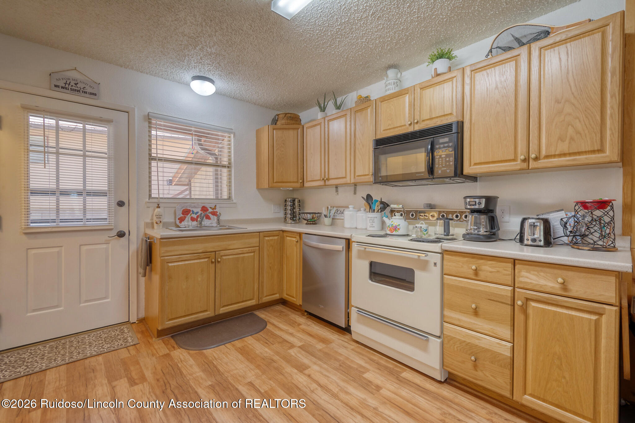 Kitchen with honey-colored cabinets, white range, microwave, and dishwasher.