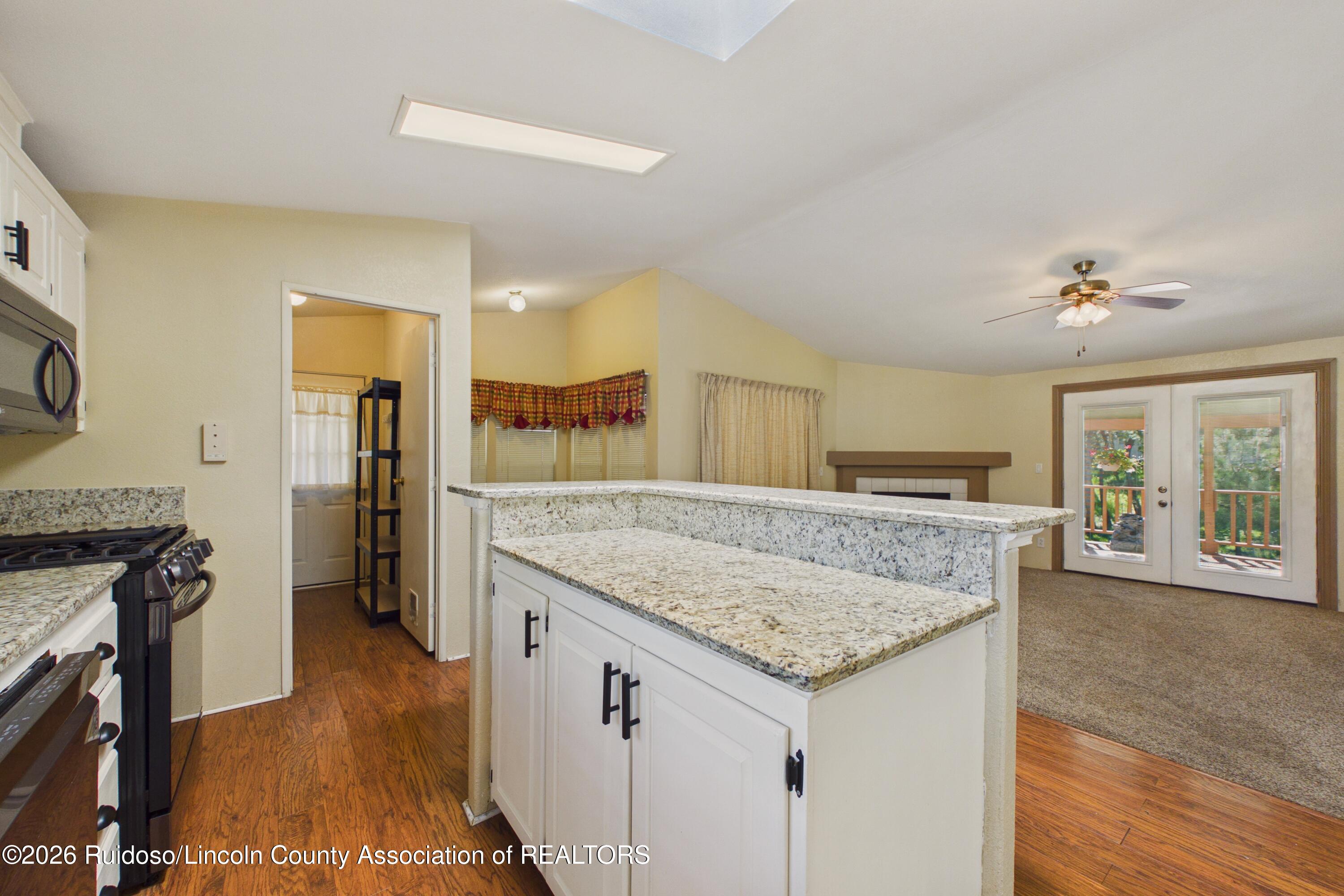 Kitchen with granite peninsula and gas range opening to a carpeted living area with deck doors.