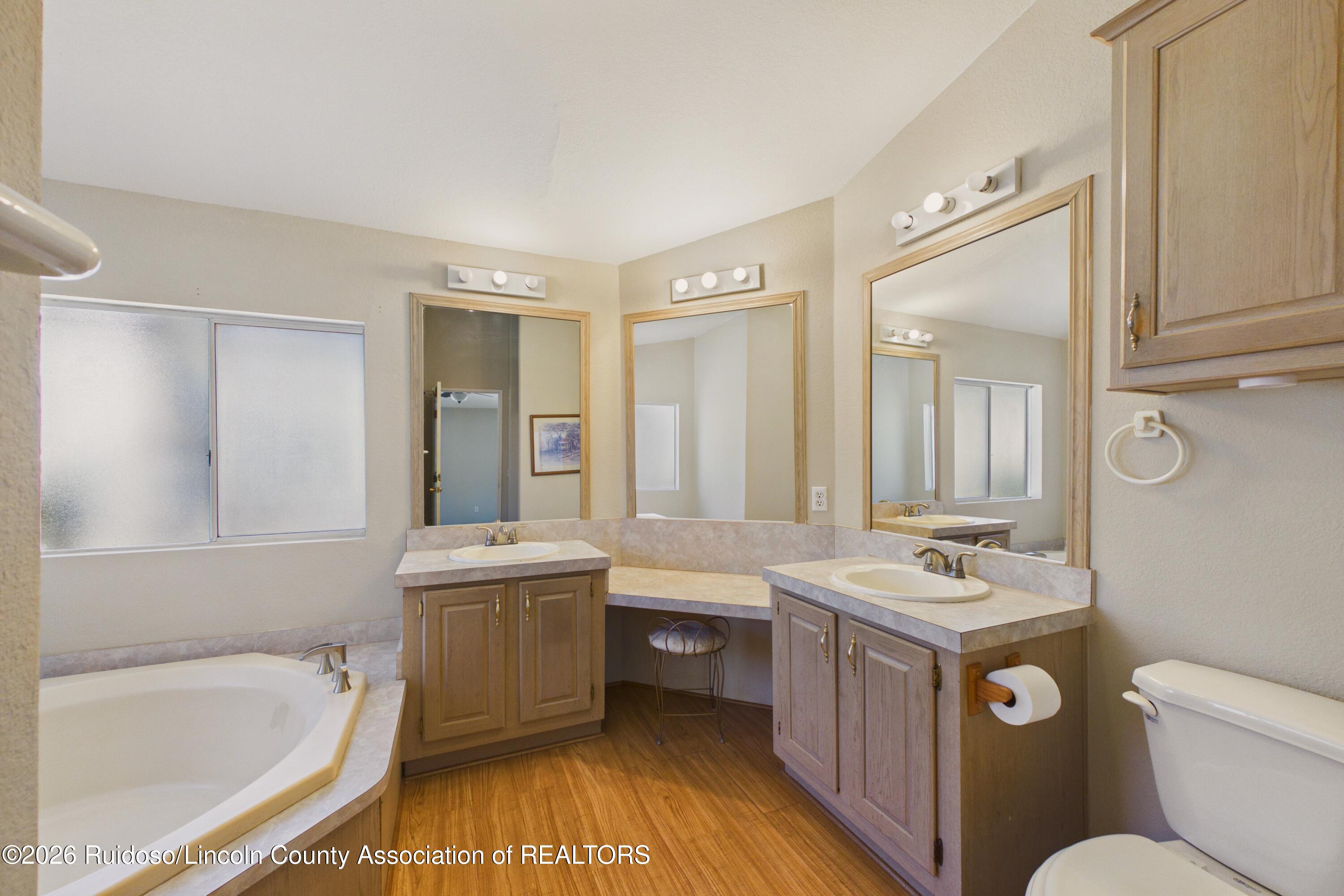 Bathroom with dual vanities, large mirrors, and a corner soaking tub.