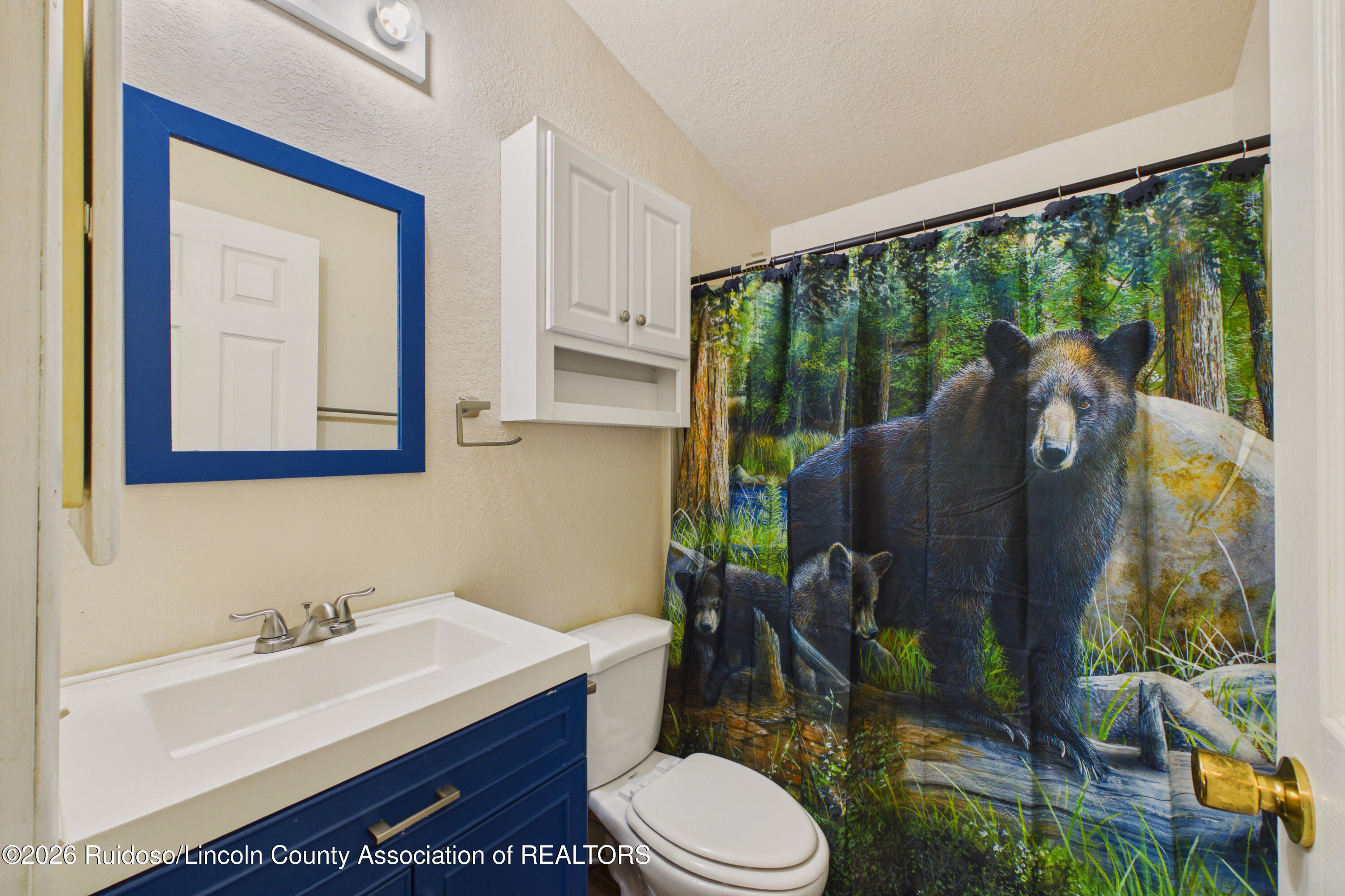Bathroom with a navy-blue vanity and a forest bear shower curtain.