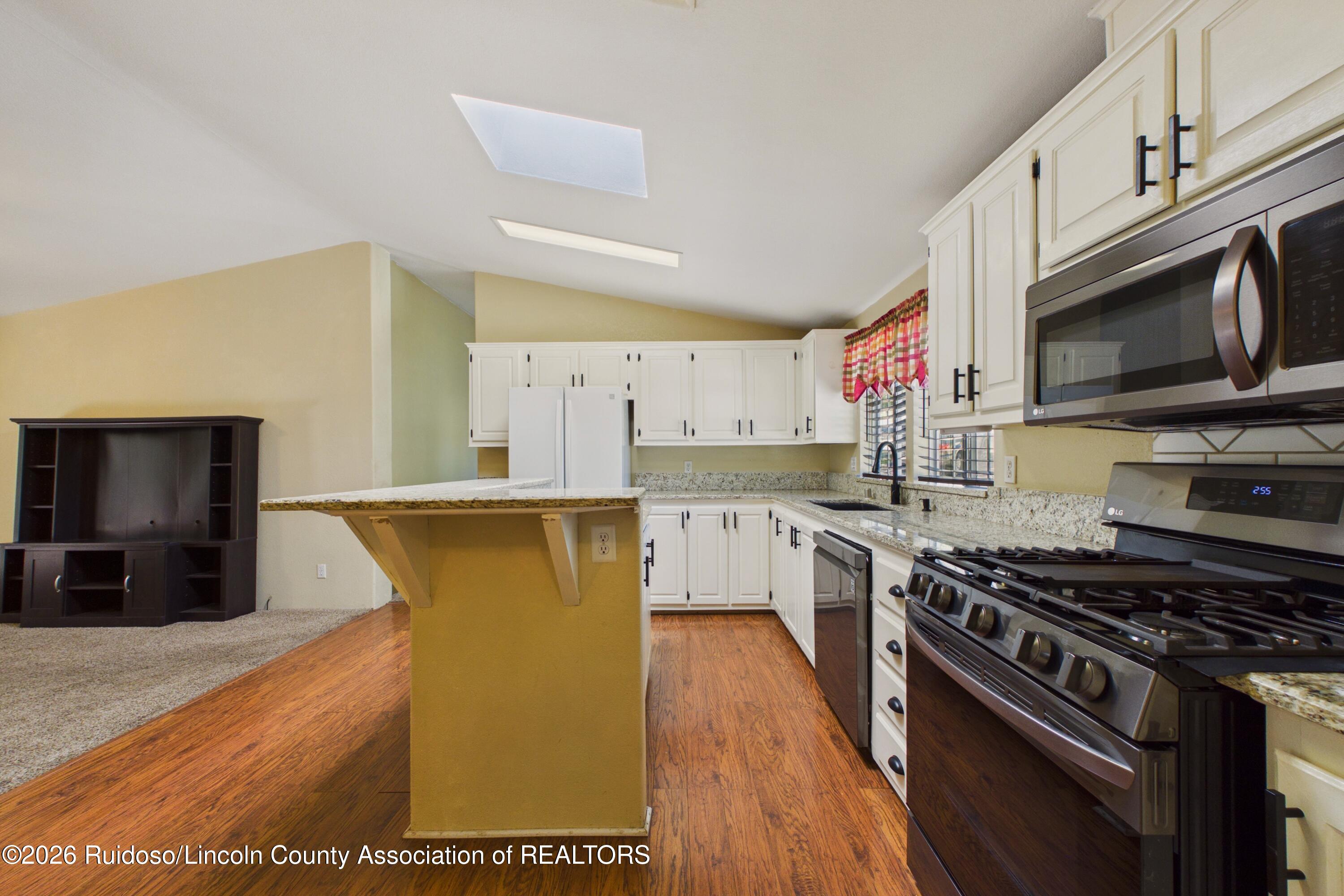 Kitchen with white cabinets, granite counters, a breakfast bar, and stainless steel appliances.