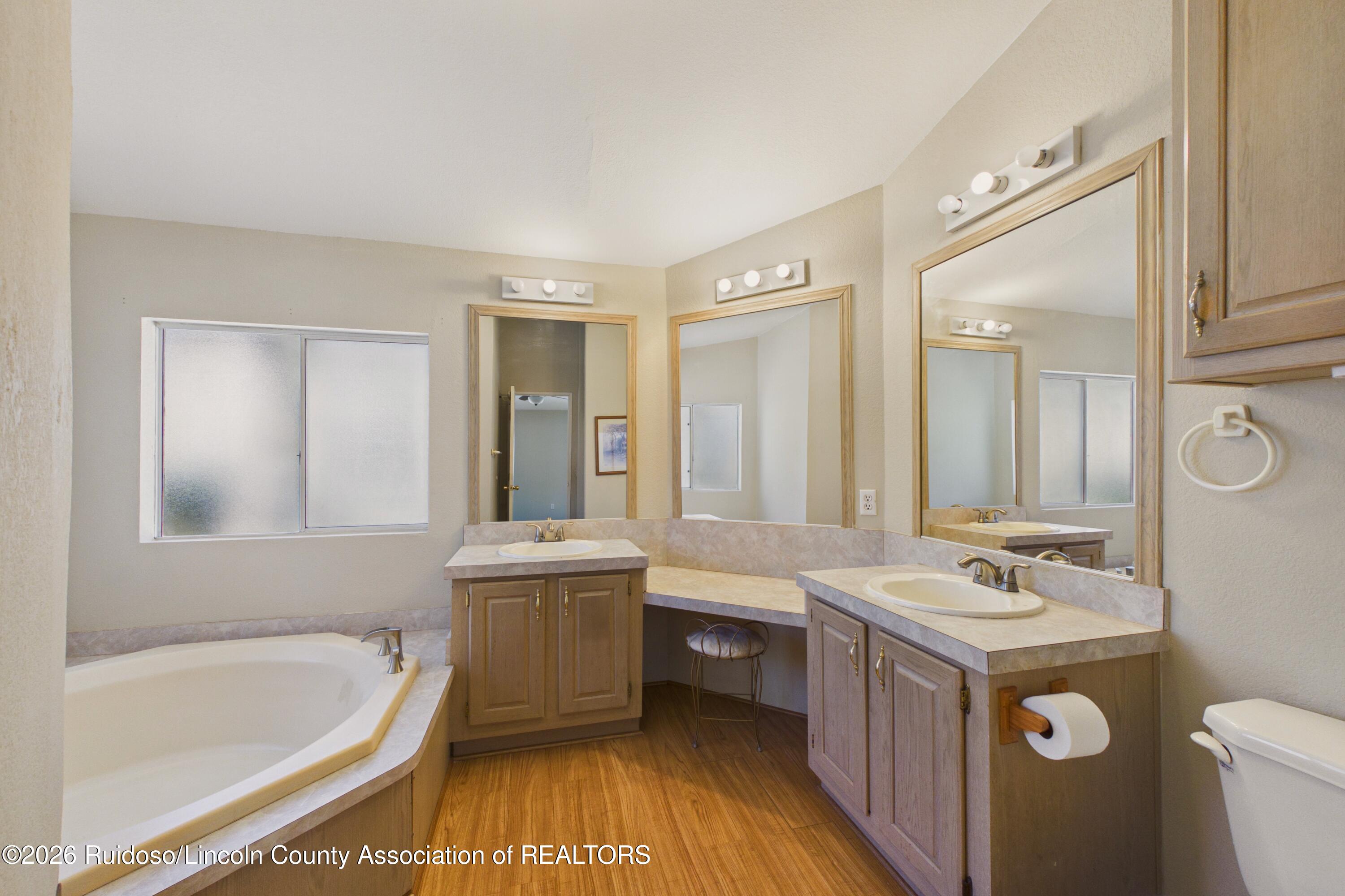 Bathroom with a corner soaking tub, two separate vanities, and large wood-framed mirrors.