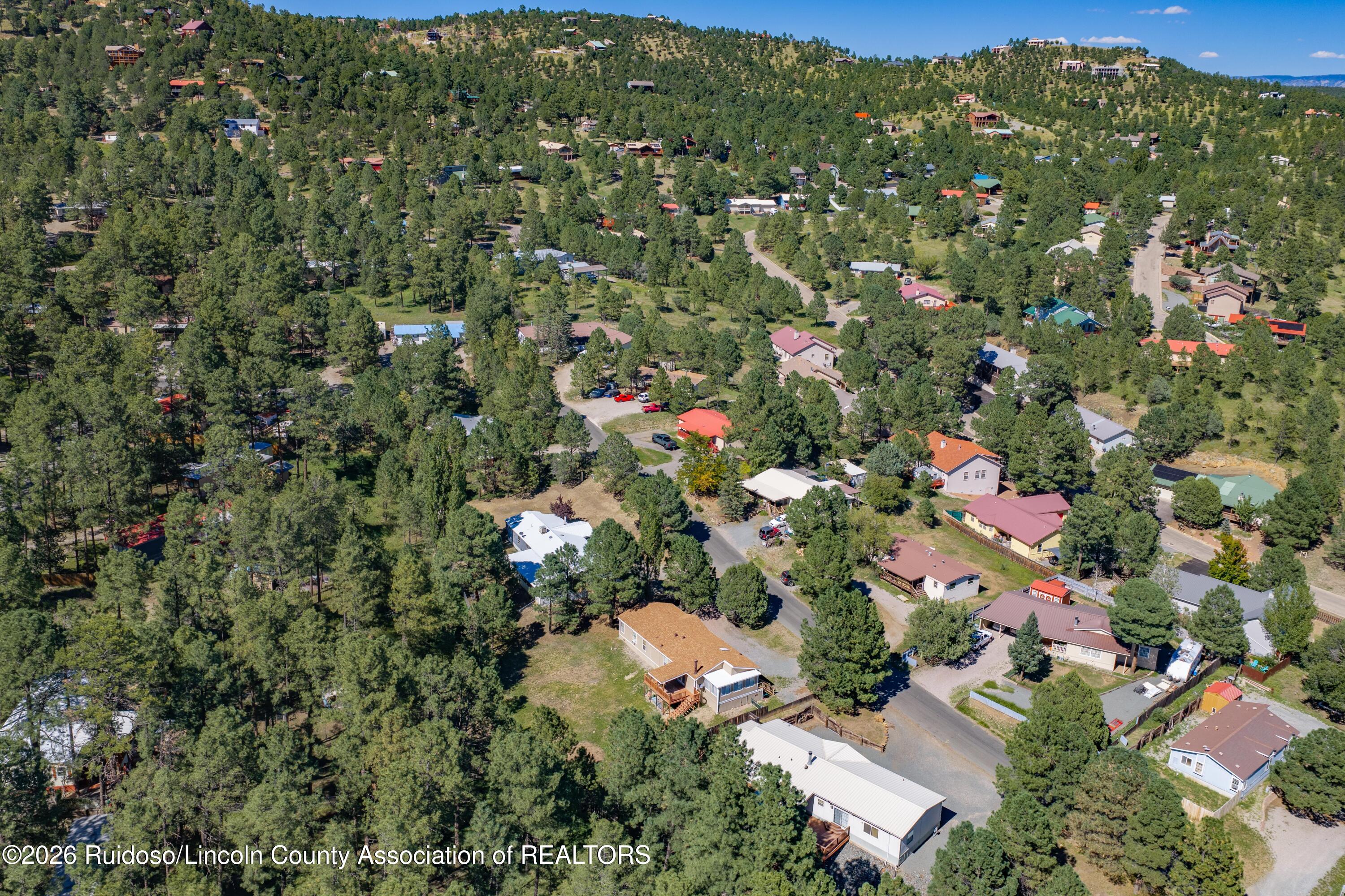 Aerial view of a wooded Ruidoso neighborhood with homes scattered along winding roads.