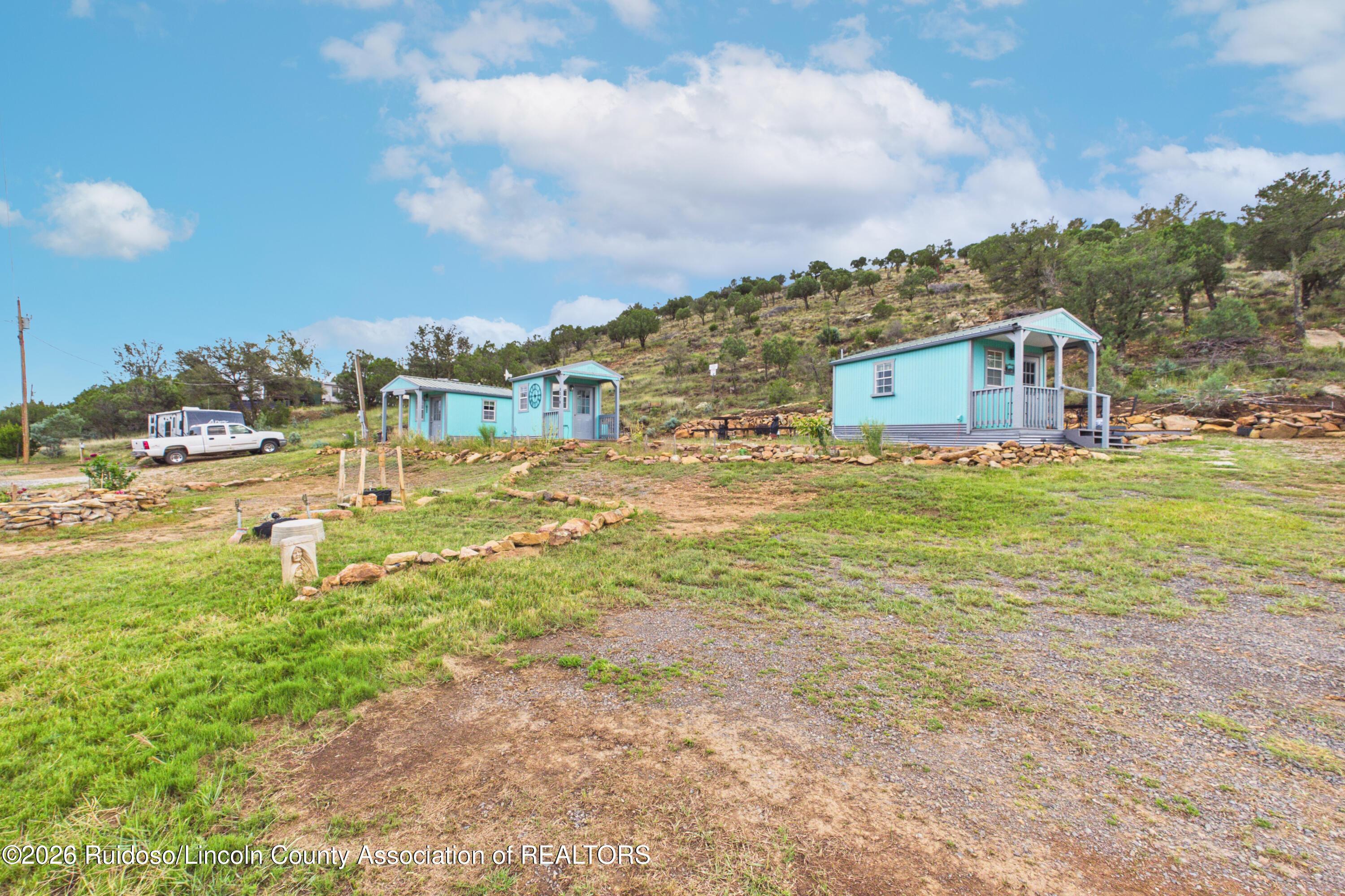 Several turquoise cabins sit on a landscaped hillside beside a gravel drive.