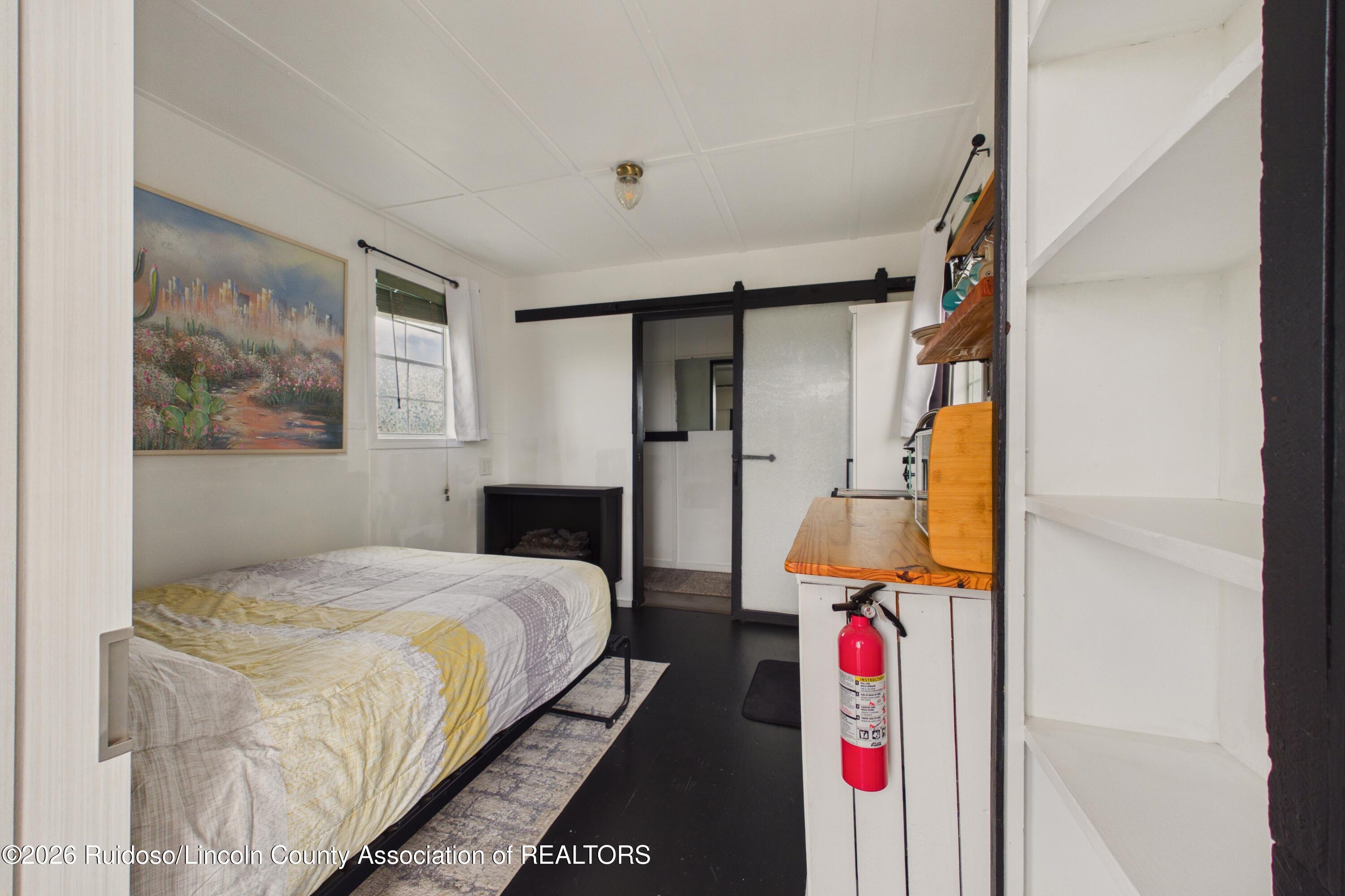 Bedroom with a patterned bed, black sliding barn door, and built-in wooden desk.