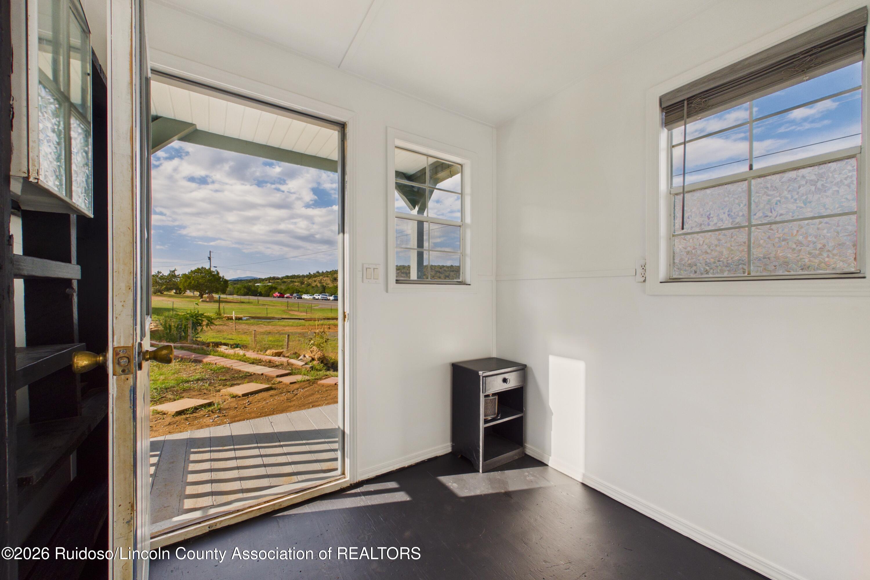 Empty white room with dark flooring and an open door to a covered patio and grassy landscape.