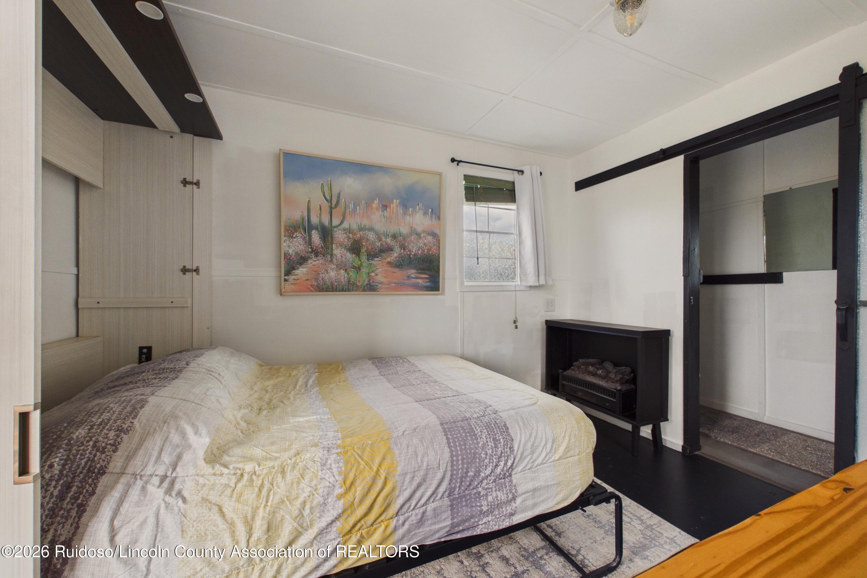 Bedroom with a large bed, desert cactus artwork, and a black sliding barn-style door.