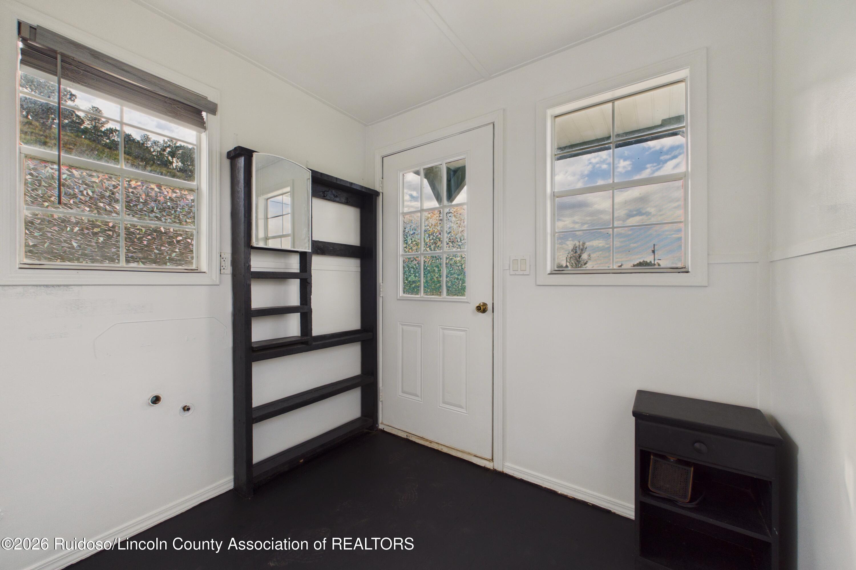 Entry room with black built-in shelving, a glazed door, and windows on either side.