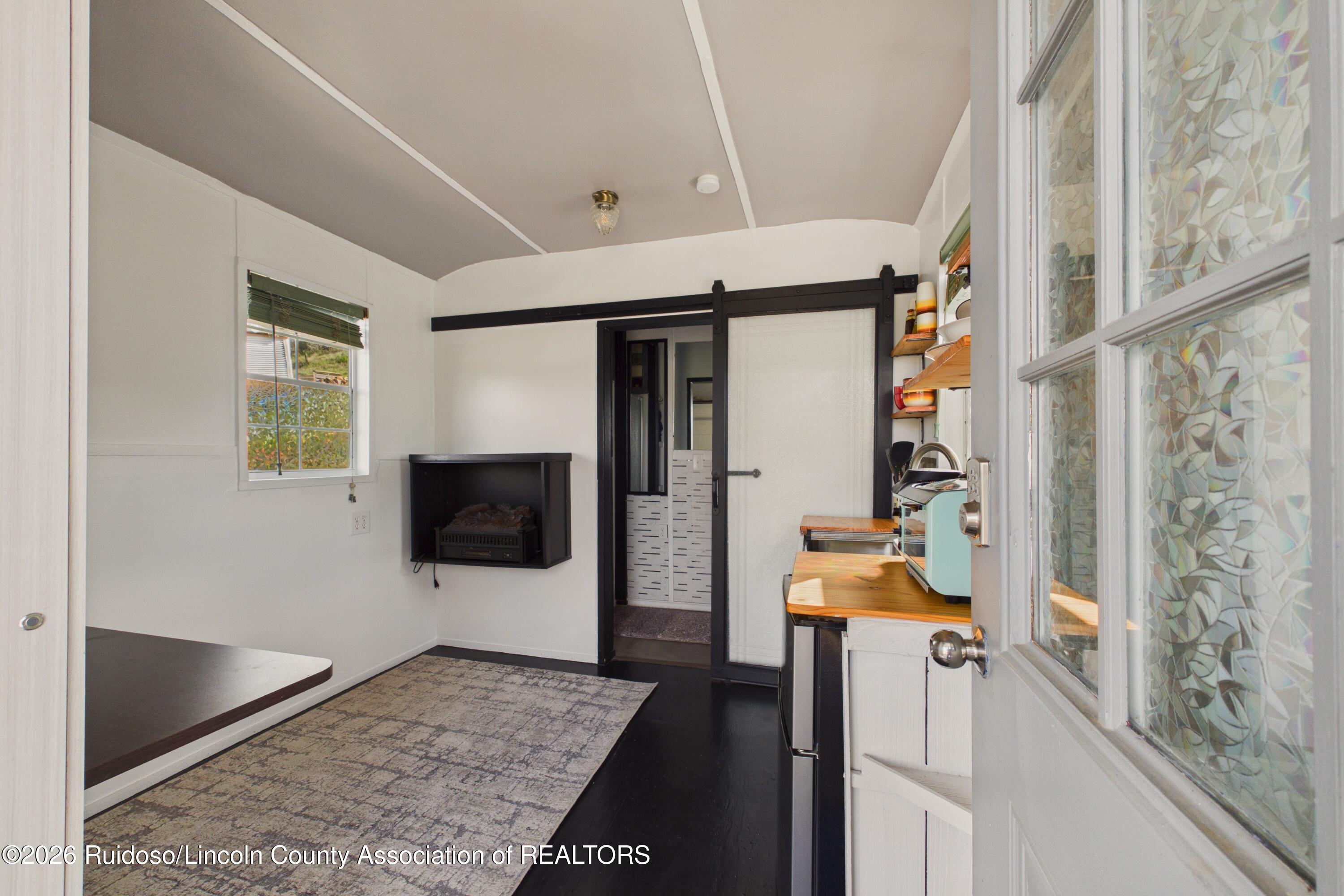 Interior room with a wood counter, mint-green coffee maker, electric fireplace, and black barn door.