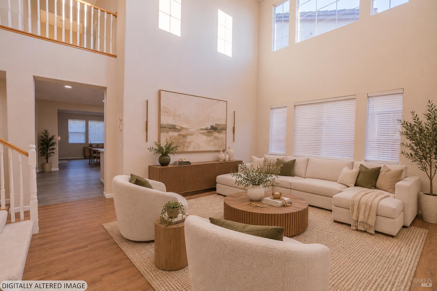 Two-story living room with a cream sectional, wood coffee table, and tall windows.
