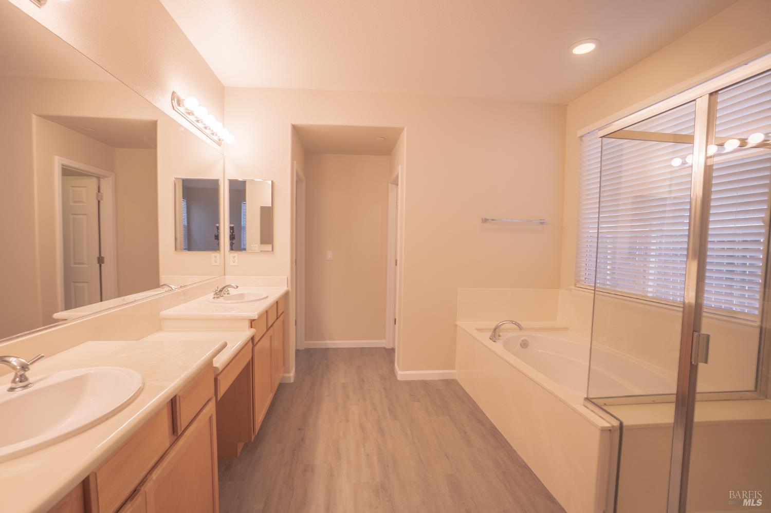 Bathroom with a long double vanity, soaking tub, and glass-enclosed shower.