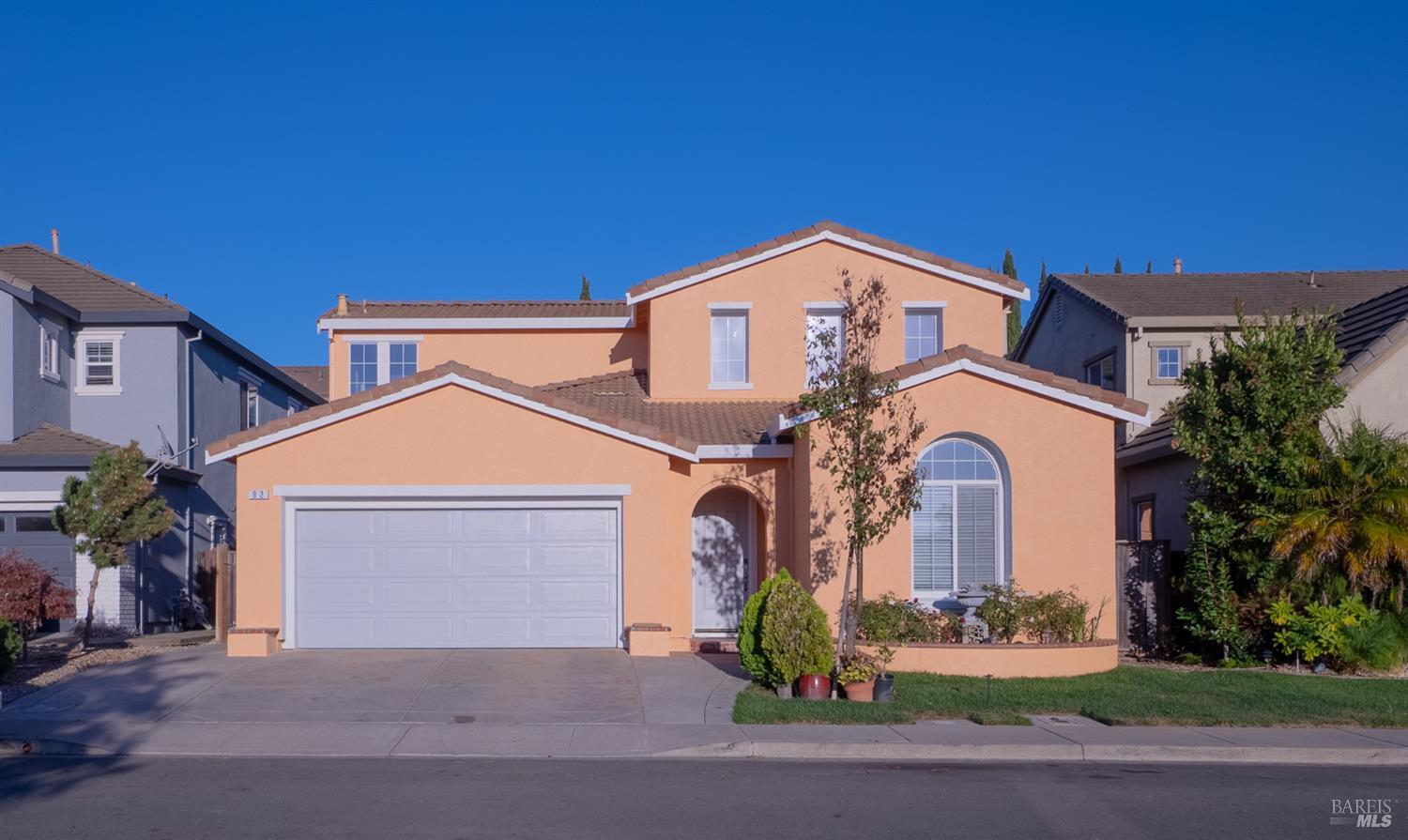 Two-story peach stucco home with an attached garage and arched front window.