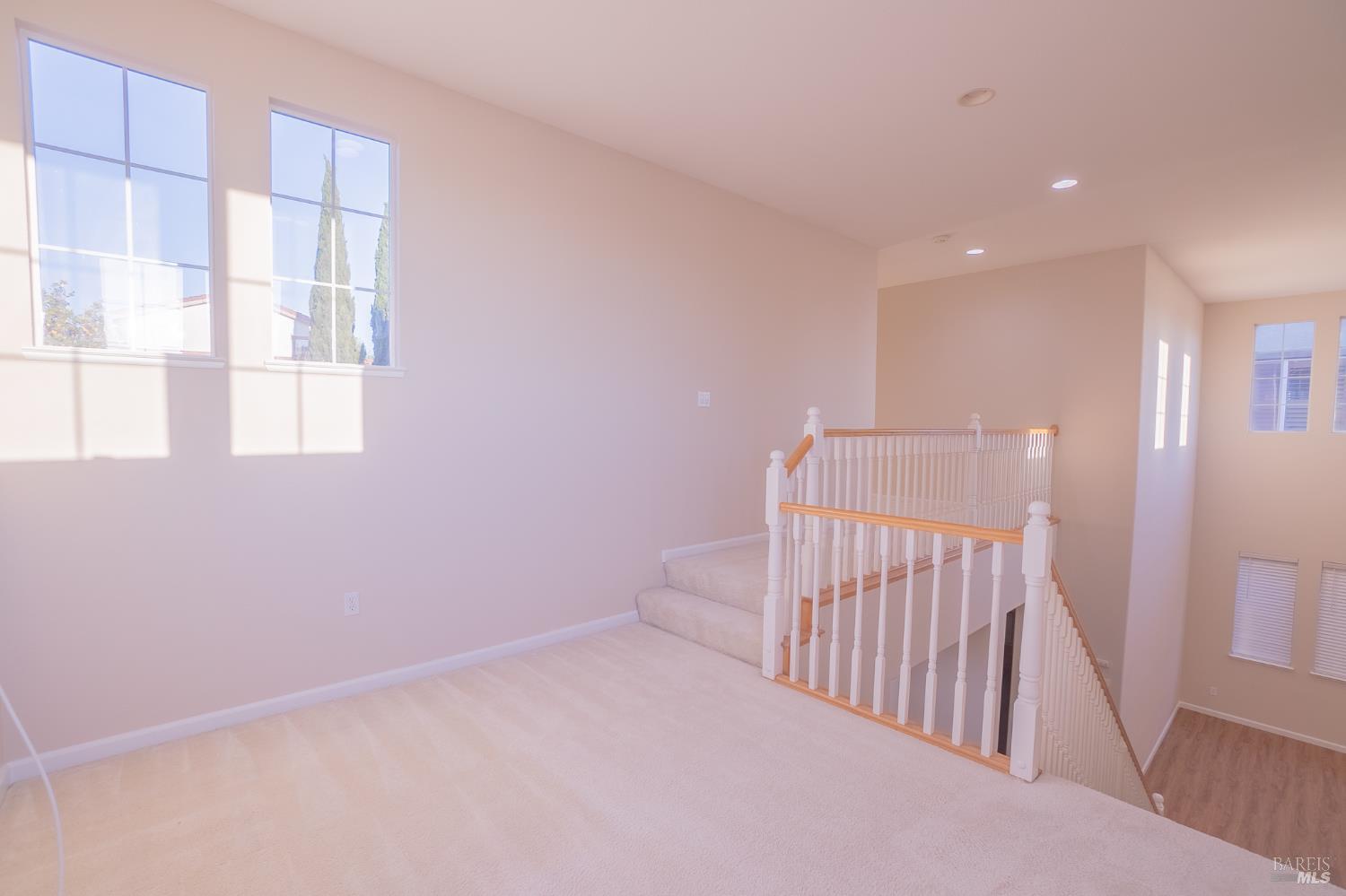 Carpeted upstairs landing with tall windows and a wood-topped staircase railing.